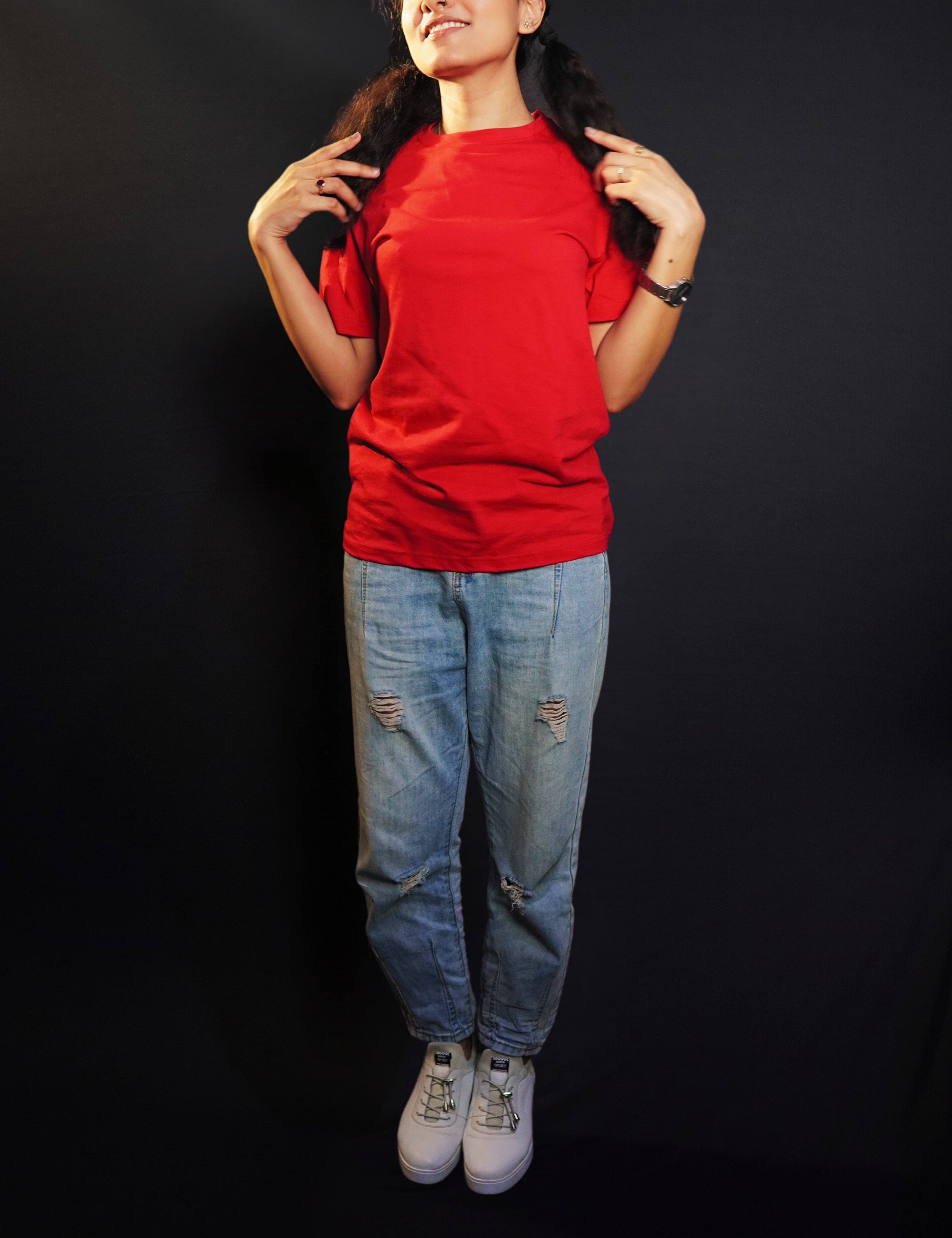 A model wearing a women's short sleeved long length rosy red t-shirt, posing with her hands grabbing sections of her hair as it lies on both of her shoulders, showcasing a modern laid back look-Muselot