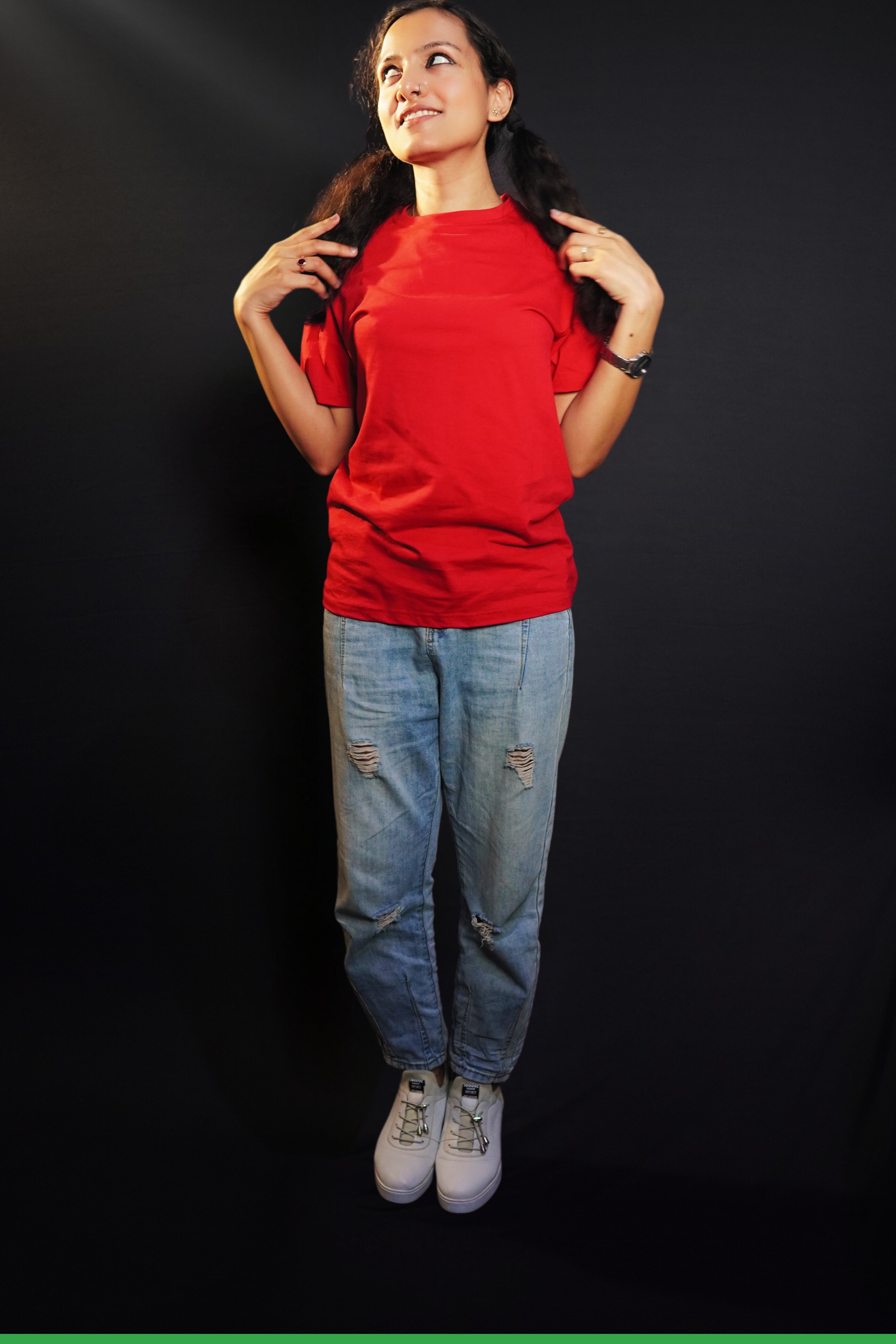 A model wearing a women's short sleeved long length rosy red t-shirt, posing with her hands grabbing sections of her hair as it lies on both of her shoulders, showcasing a modern laid back look-Muselot