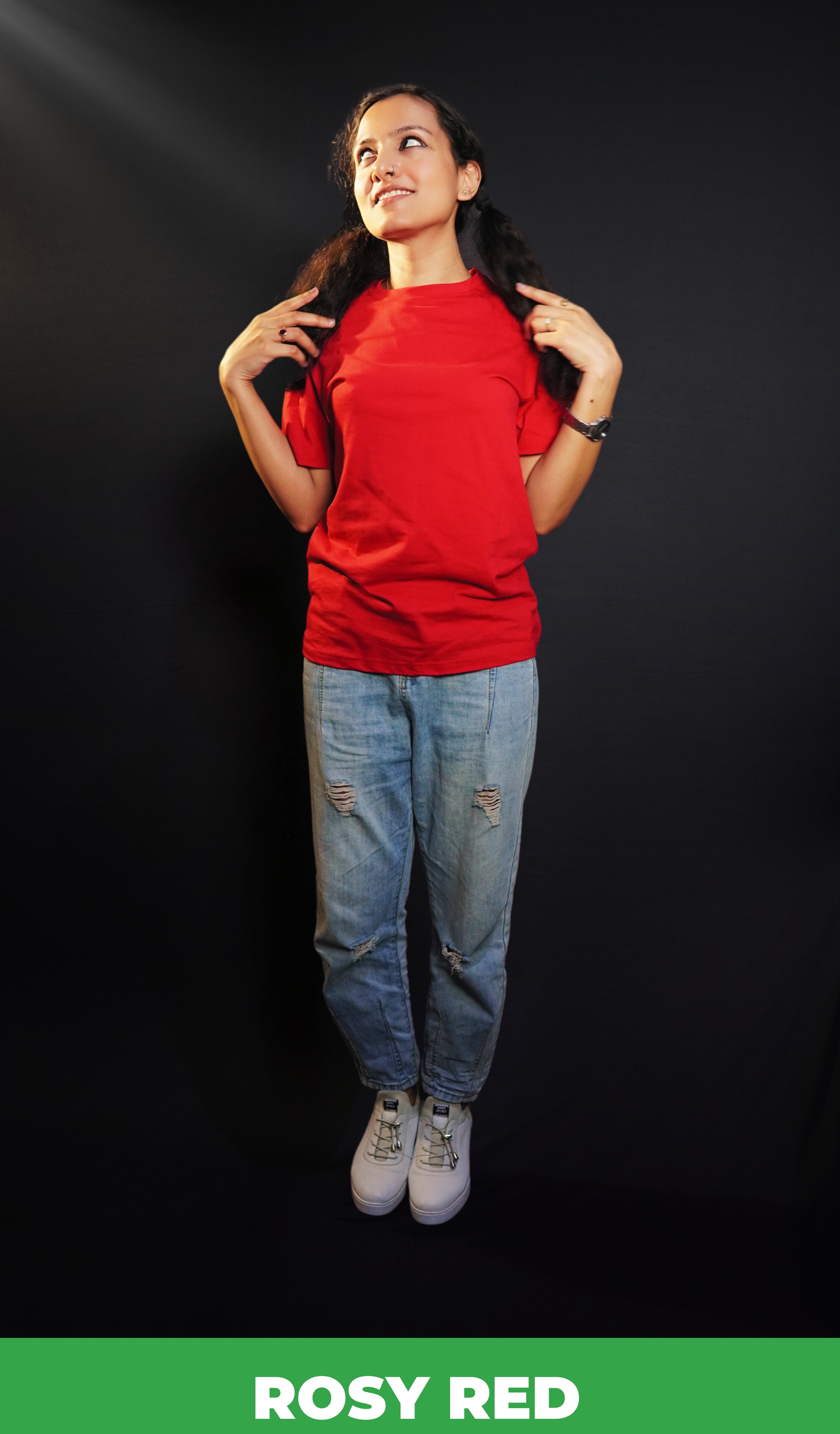 A model wearing a women's short sleeved long length rosy red t-shirt, posing with her hands grabbing sections of her hair as it lies on both of her shoulders, showcasing a modern laid back look-Muselot
