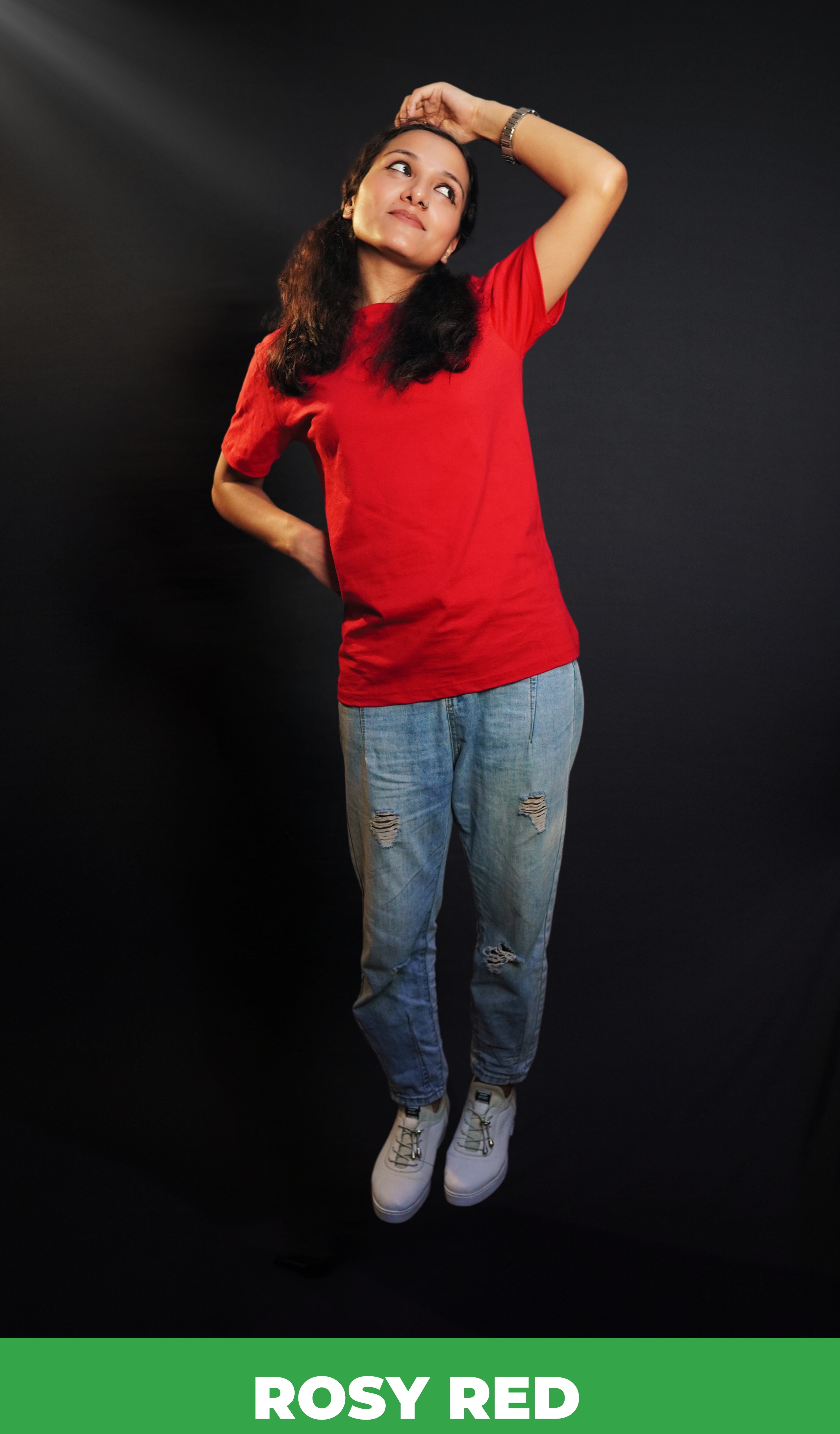 A woman wearing a unisex cotton long length stretchable rosy red t-shirt, posing with her hand on her head and other behind her waist looking sideways with her head up and bent slightly to her side, showcasing a trendy casual fit-Muselot