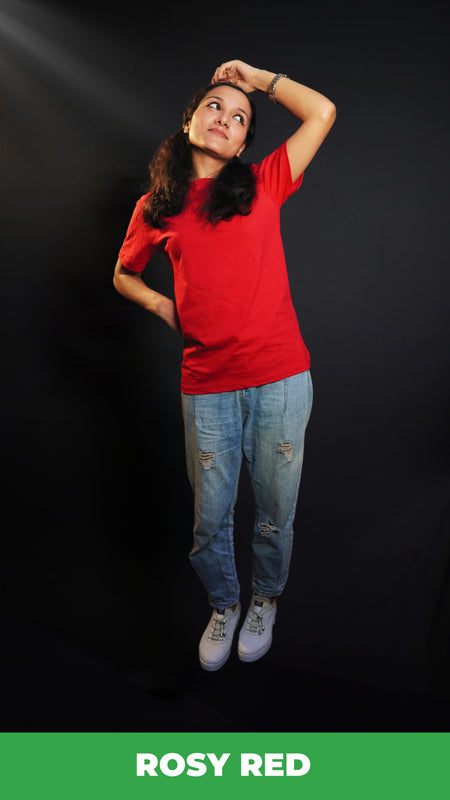 A woman wearing a men's cotton long length stretchable rosy red t-shirt, posing with her hand on her head and other behind her waist looking sideways with her head up and bent slightly to her side, showcasing a trendy casual fit-Muselot
