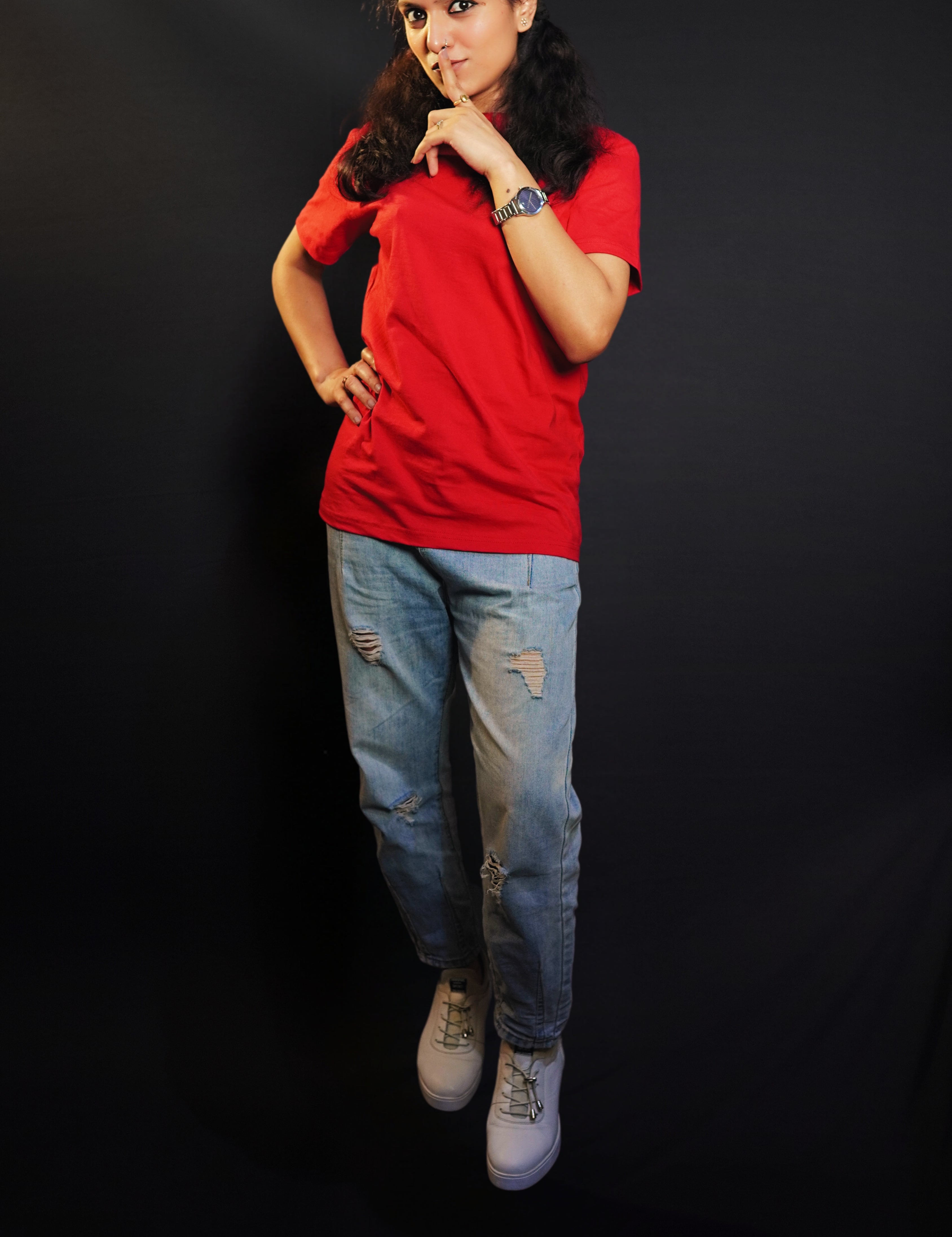 A woman posing with her finger on her lips and a hand on her waist, wearing a plus size round neck stretchable rosy red t-shirt, showcasing a popular easygoing fit-Muselot