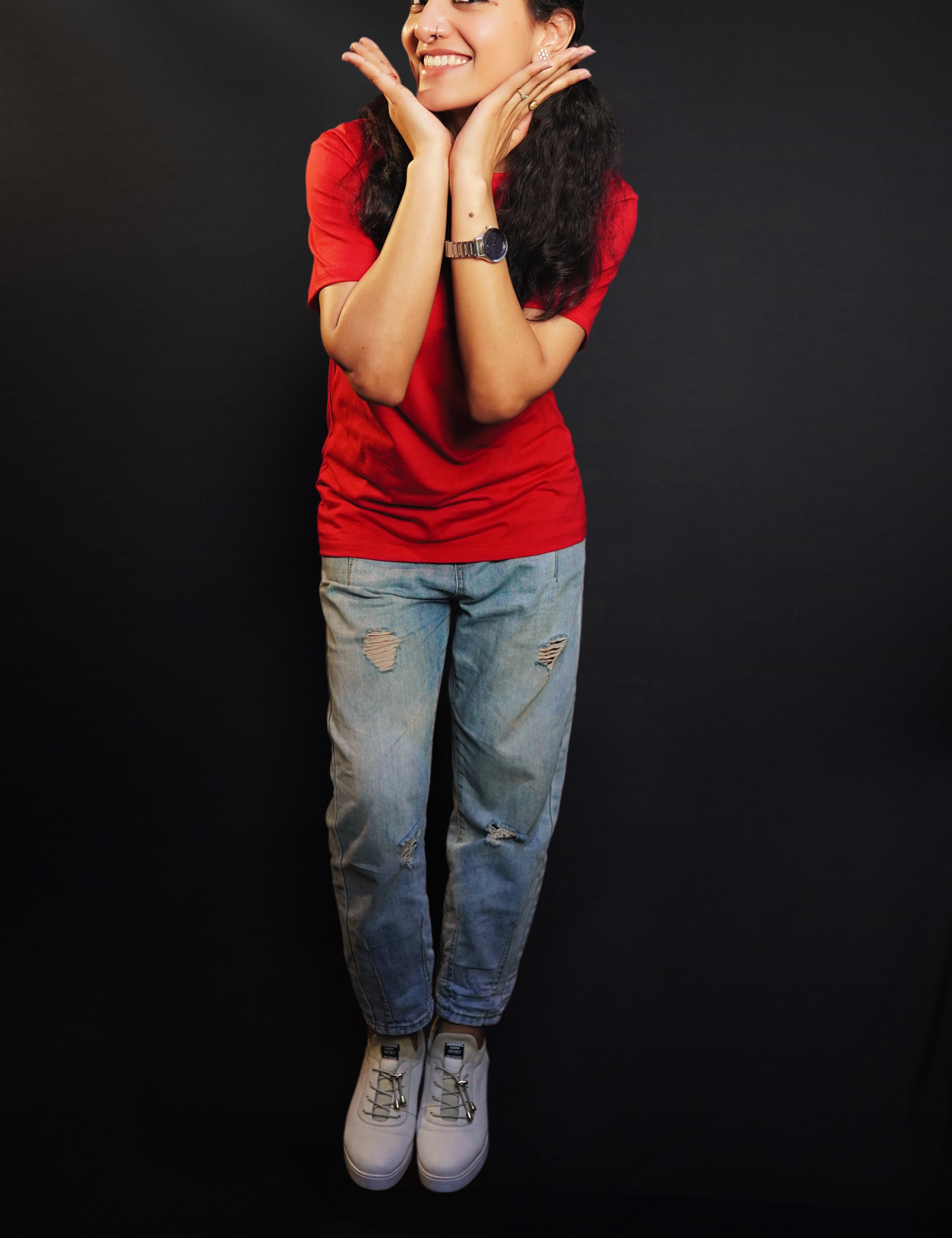 A woman posing happily with her hands under her chin as she bends slightly forward, wearing a summer rosy red t-shirt with round neck and short sleeves, highlighting a casual cozy fit-Muselot