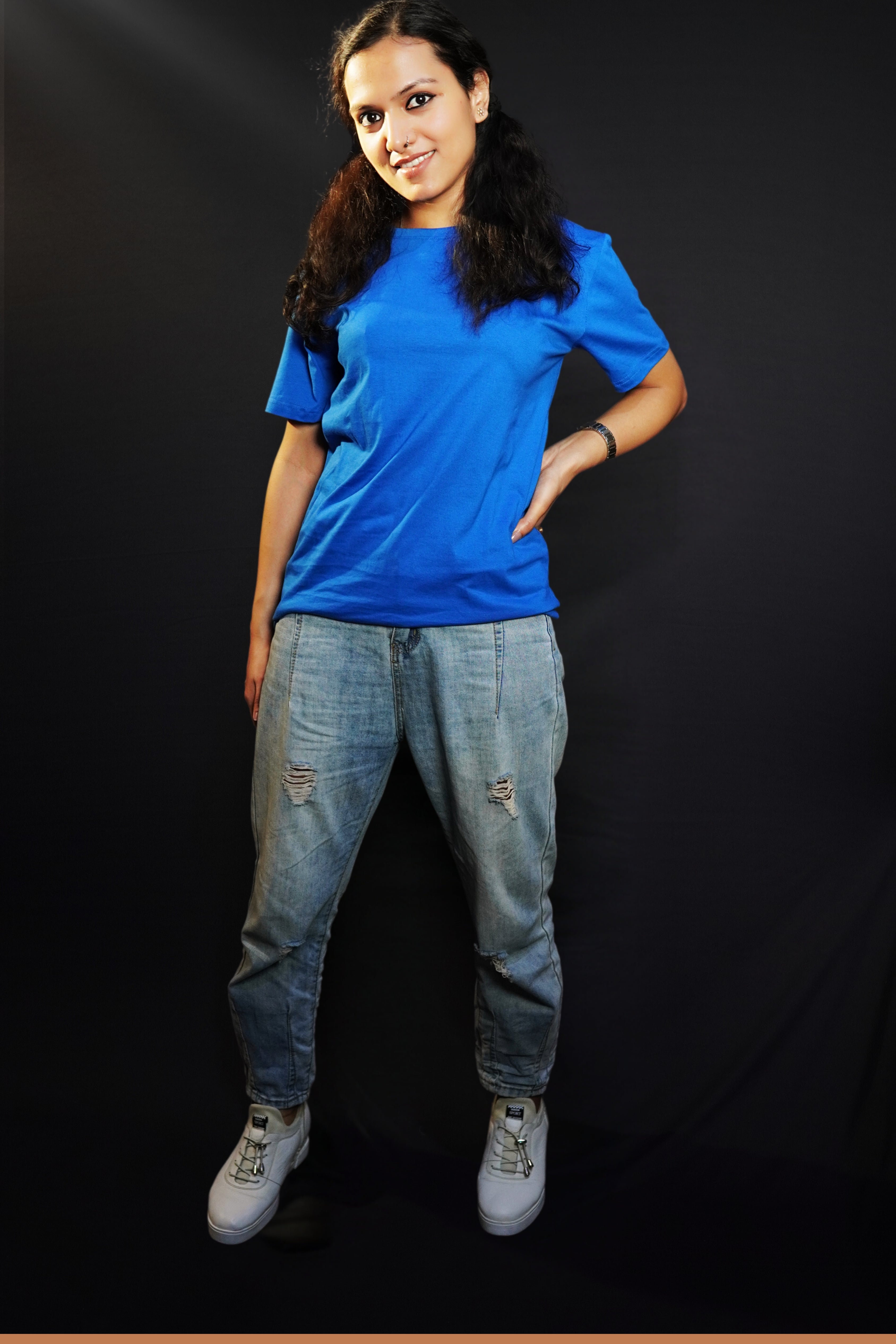 A woman wearing a cotton short sleeved round neck long t-shirt, posing with her hand on her waist and another hanging behind her, highlighting a modish slouchy fit-Muselot
