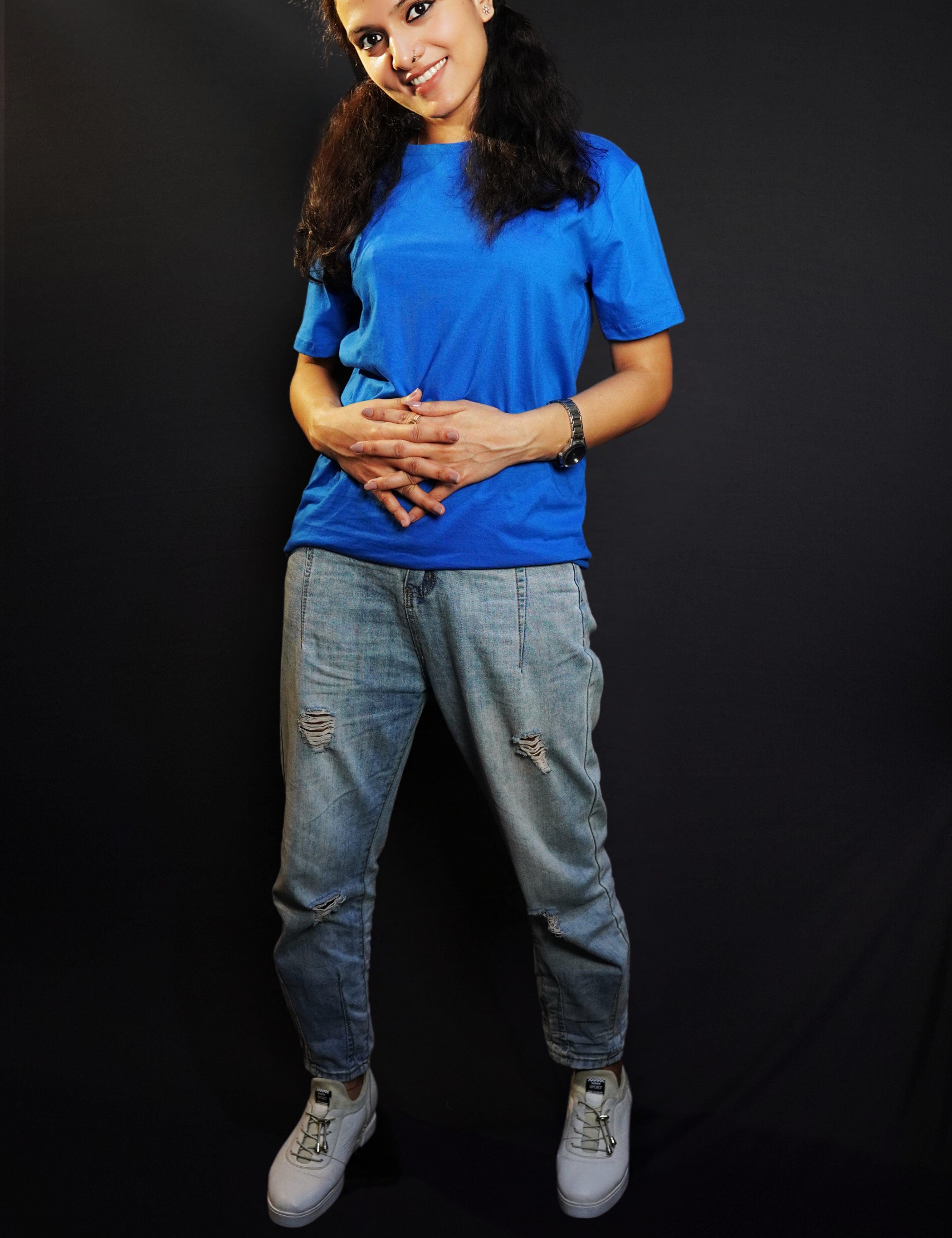 A woman smiling with her head bent down slightly and fingers intertwined with each other, wearing a royal blue plain quick drying moisture wicking t-shirt, showcasing a fashionable perfect fit-Muselot