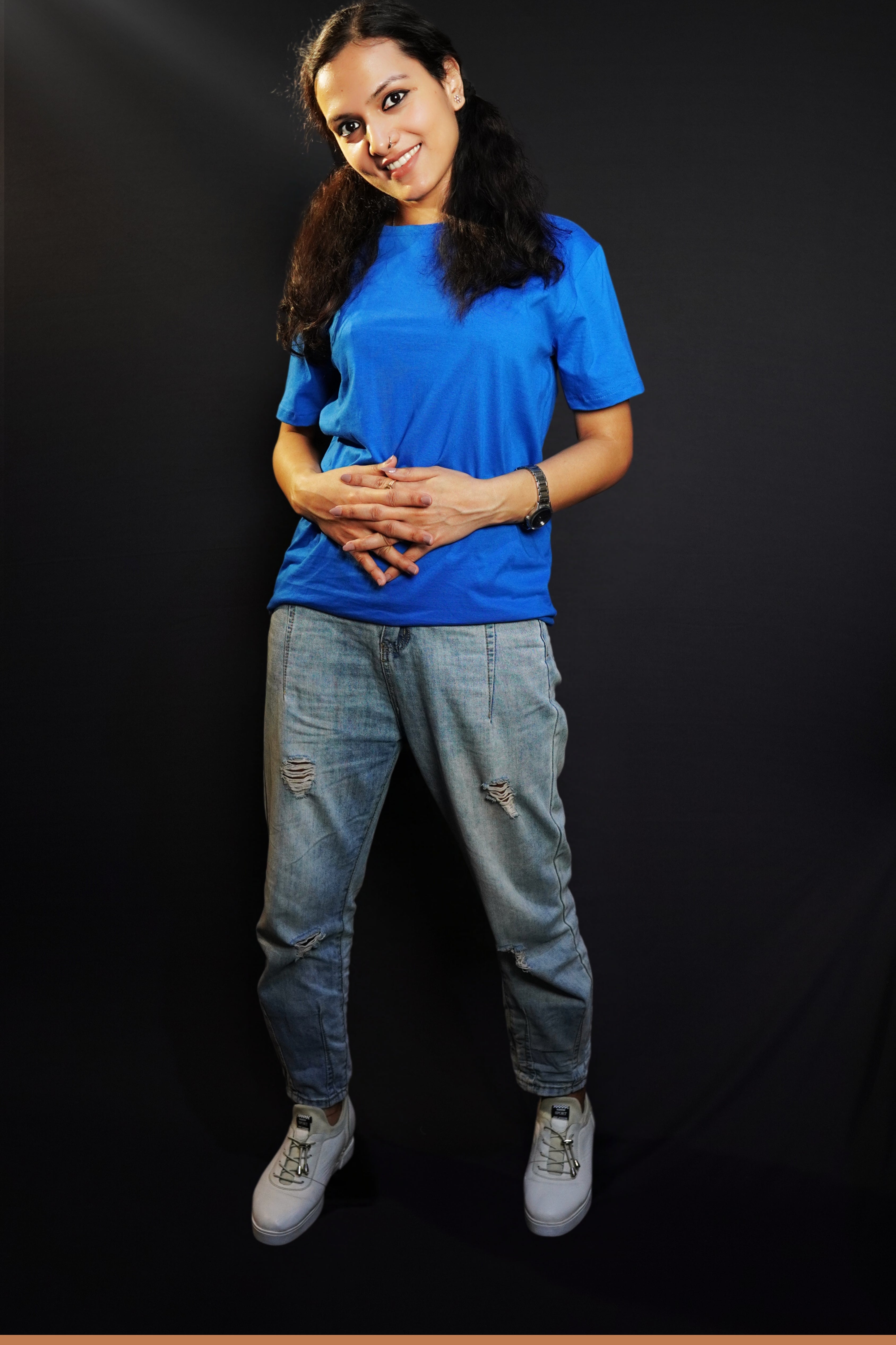 A woman smiling with her head bent down slightly and fingers intertwined with each other, wearing a royal blue plain quick drying moisture wicking t-shirt, showcasing a fashionable perfect fit-Muselot