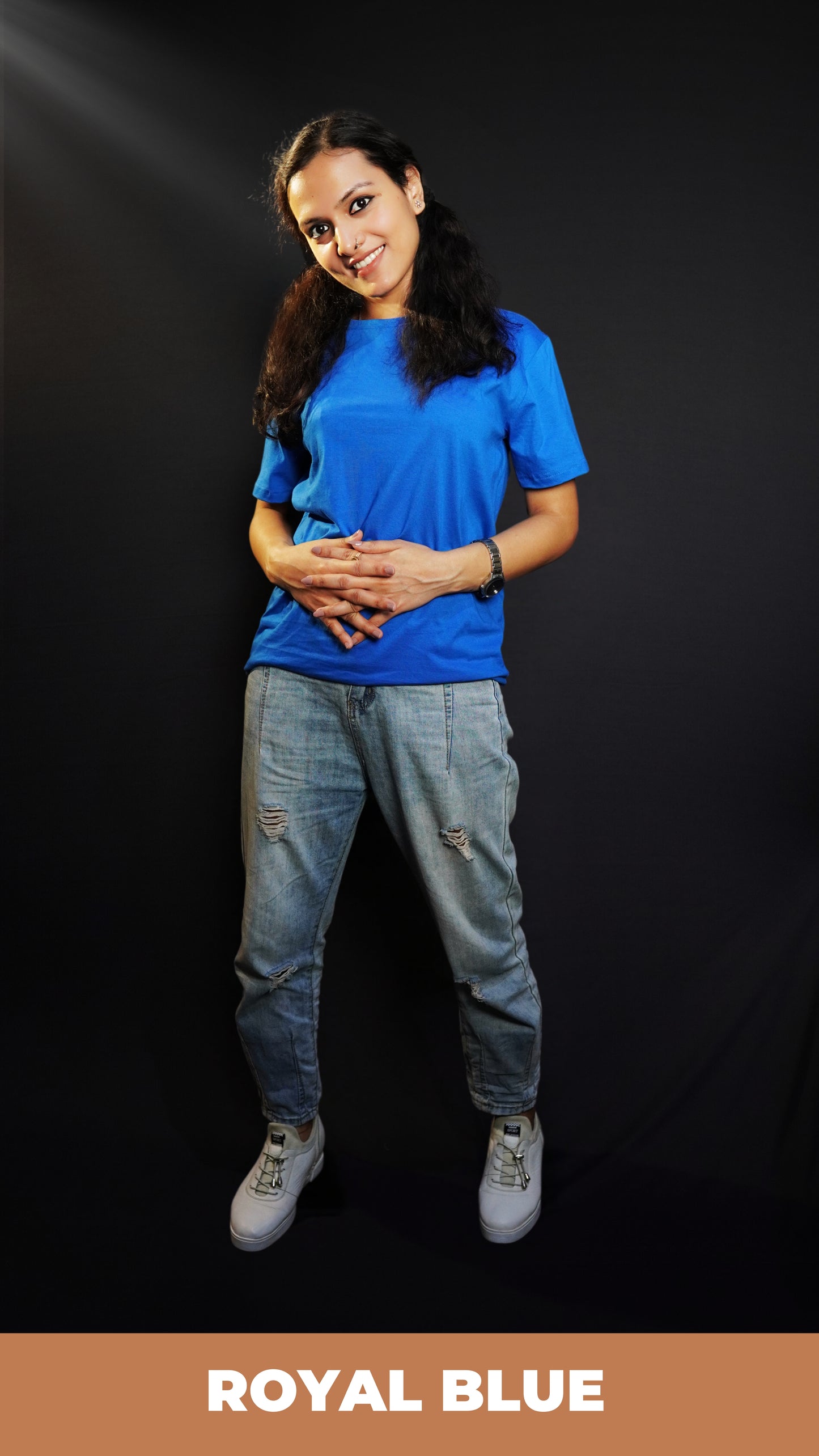 A woman smiling with her head bent down slightly and fingers intertwined with each other, wearing a royal blue plain quick drying moisture wicking t-shirt, showcasing a fashionable perfect fit-Muselot