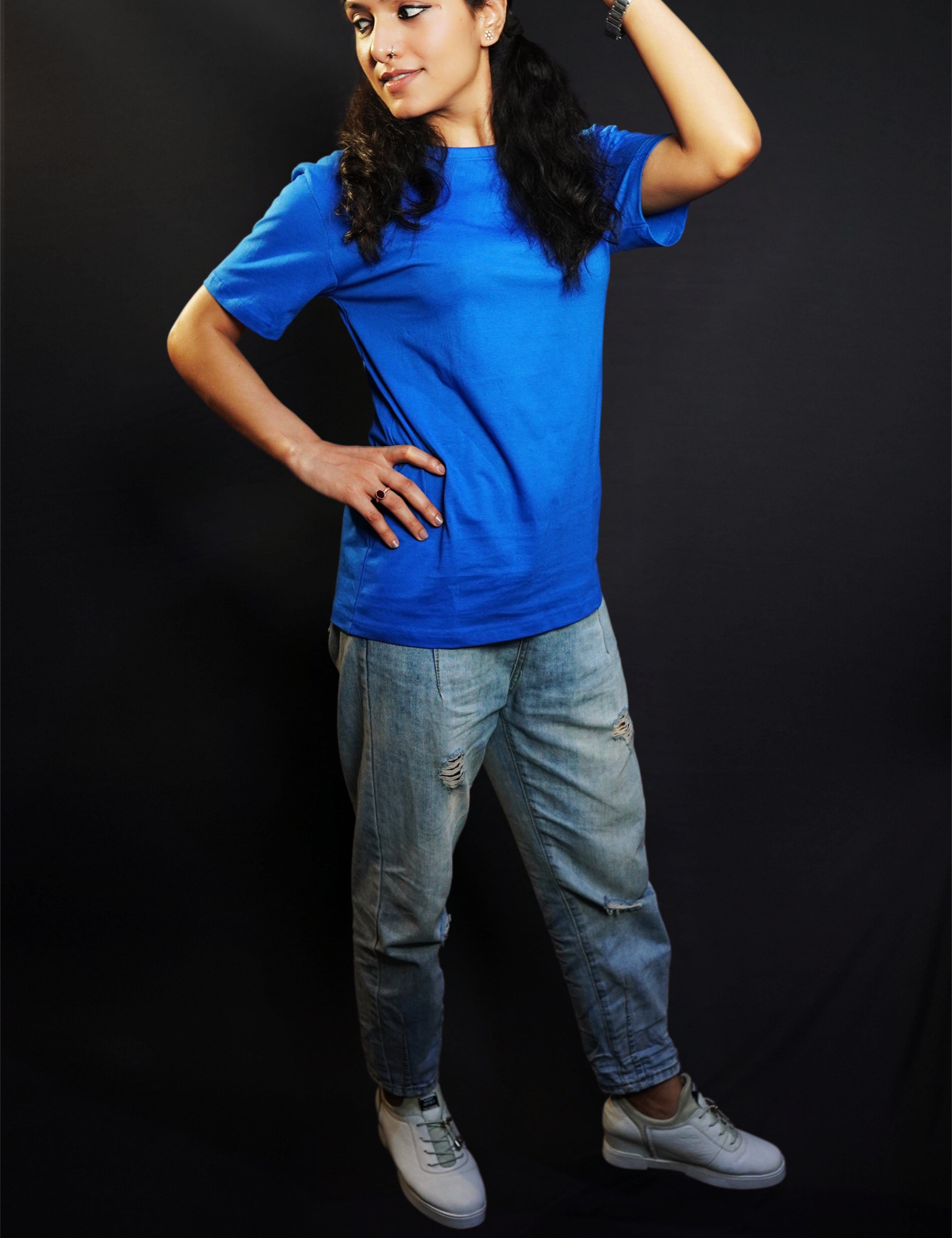 A woman wearing a unisex plain cotton round neck royal blue t-shirt, posing with her hand on her head and another on her waist as she looks sideways, highlighting a summer casual fit-Muselot