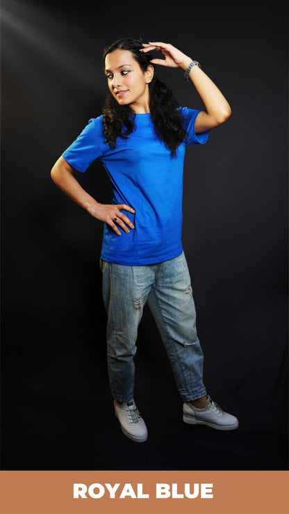 A woman wearing a unisex plain cotton round neck royal blue t-shirt, posing with her hand on her head and another on her waist as she looks sideways, highlighting a summer casual fit-Muselot