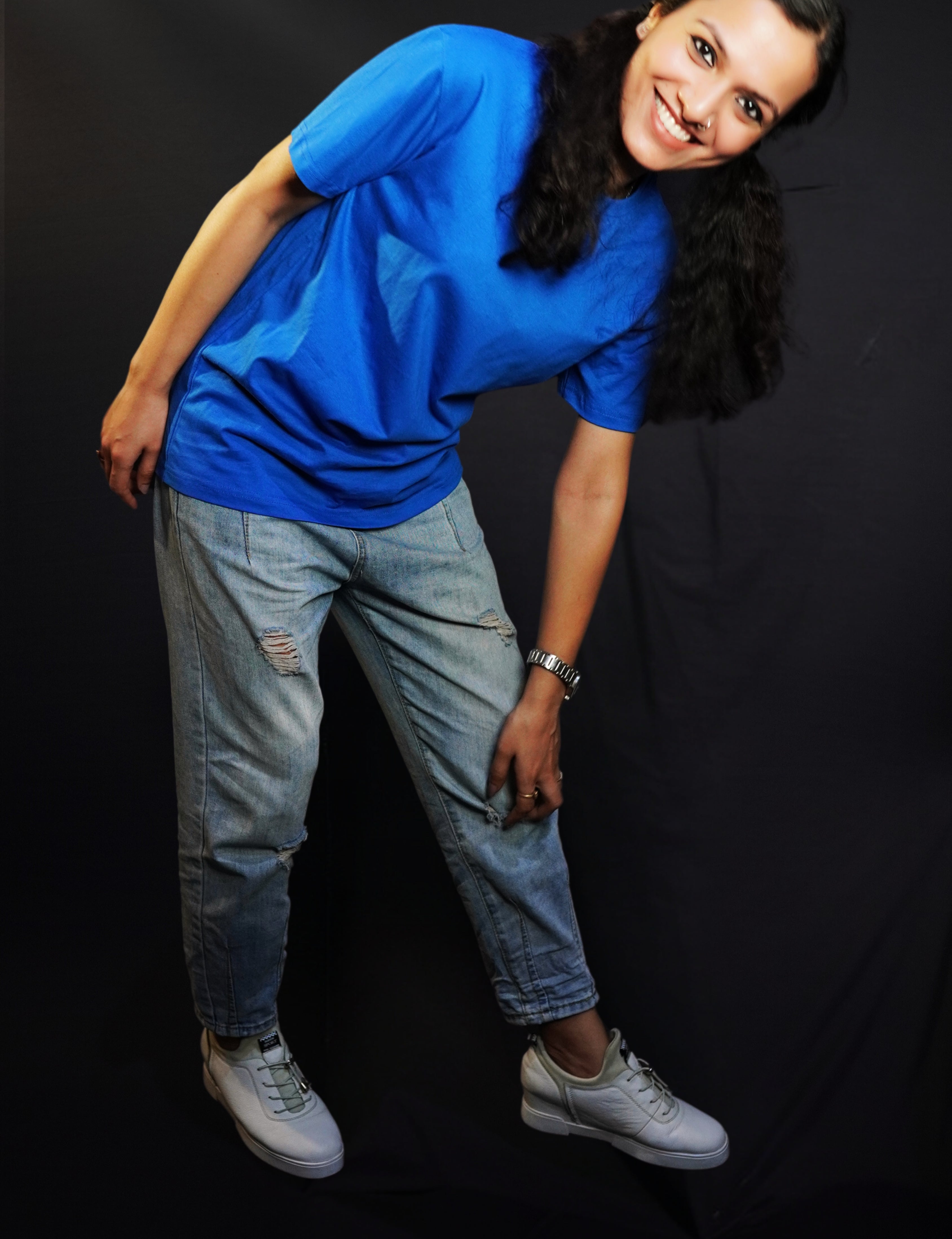 A woman bending forward with her hand touching her knee smiling brightly, wearing a women's round neck short sleeved royal blue t-shirt, showcasing a comfortable snug fit-Muselot