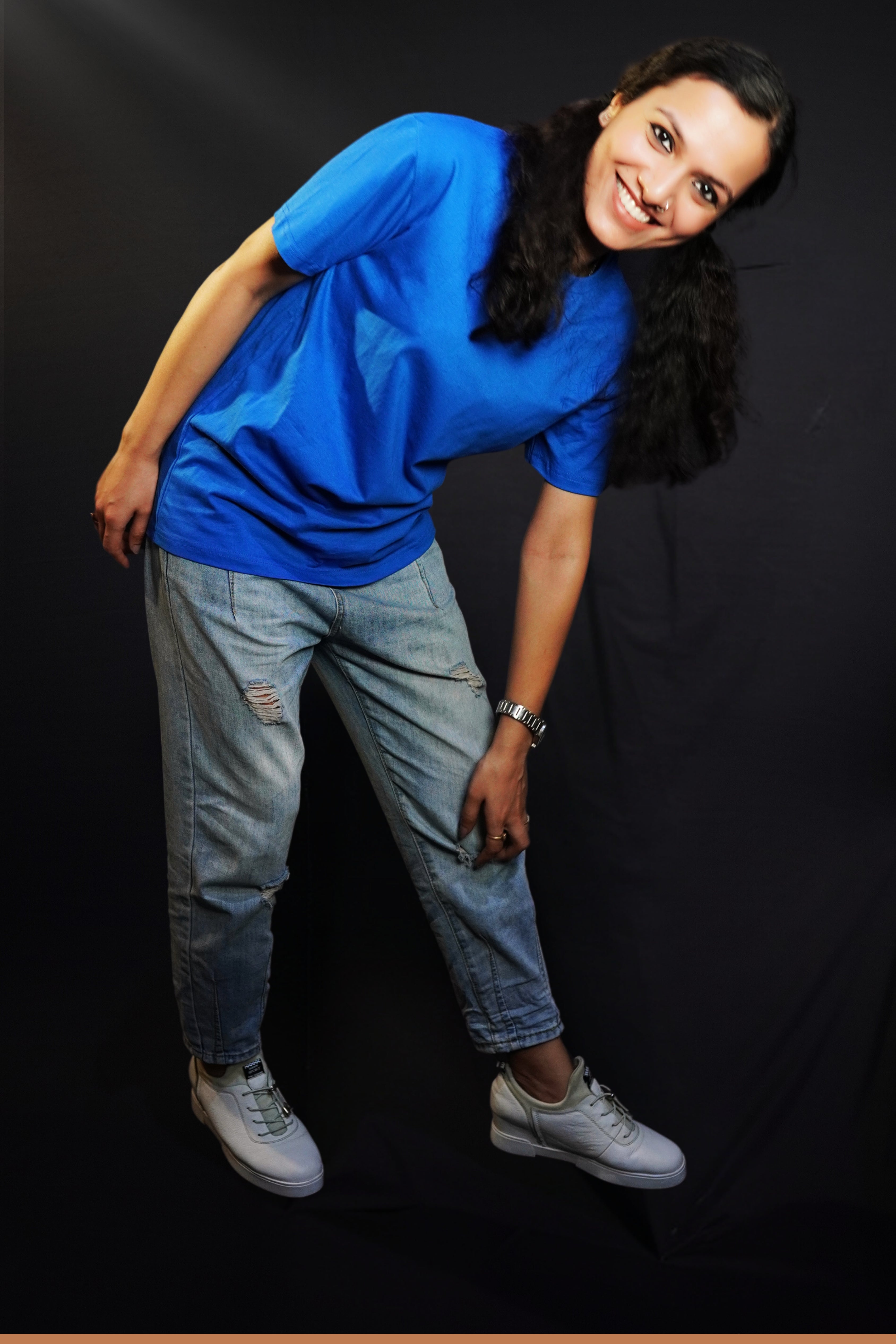 A woman bending forward with her hand touching her knee smiling brightly, wearing a women's round neck short sleeved royal blue t-shirt, showcasing a comfortable snug fit-Muselot