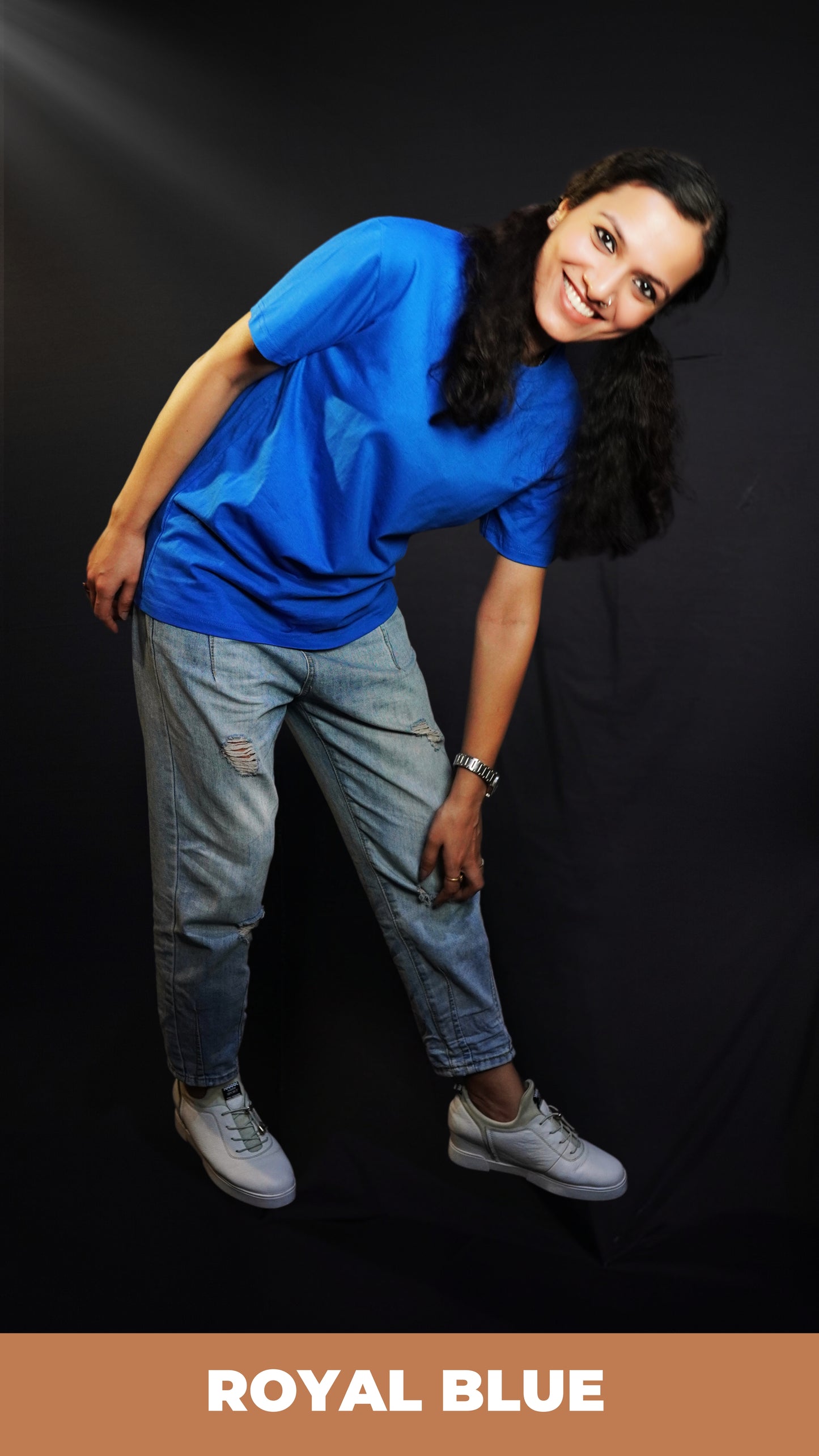 A woman bending forward with her hand touching her knee smiling brightly, wearing a women's round neck short sleeved royal blue t-shirt, showcasing a comfortable snug fit-Muselot