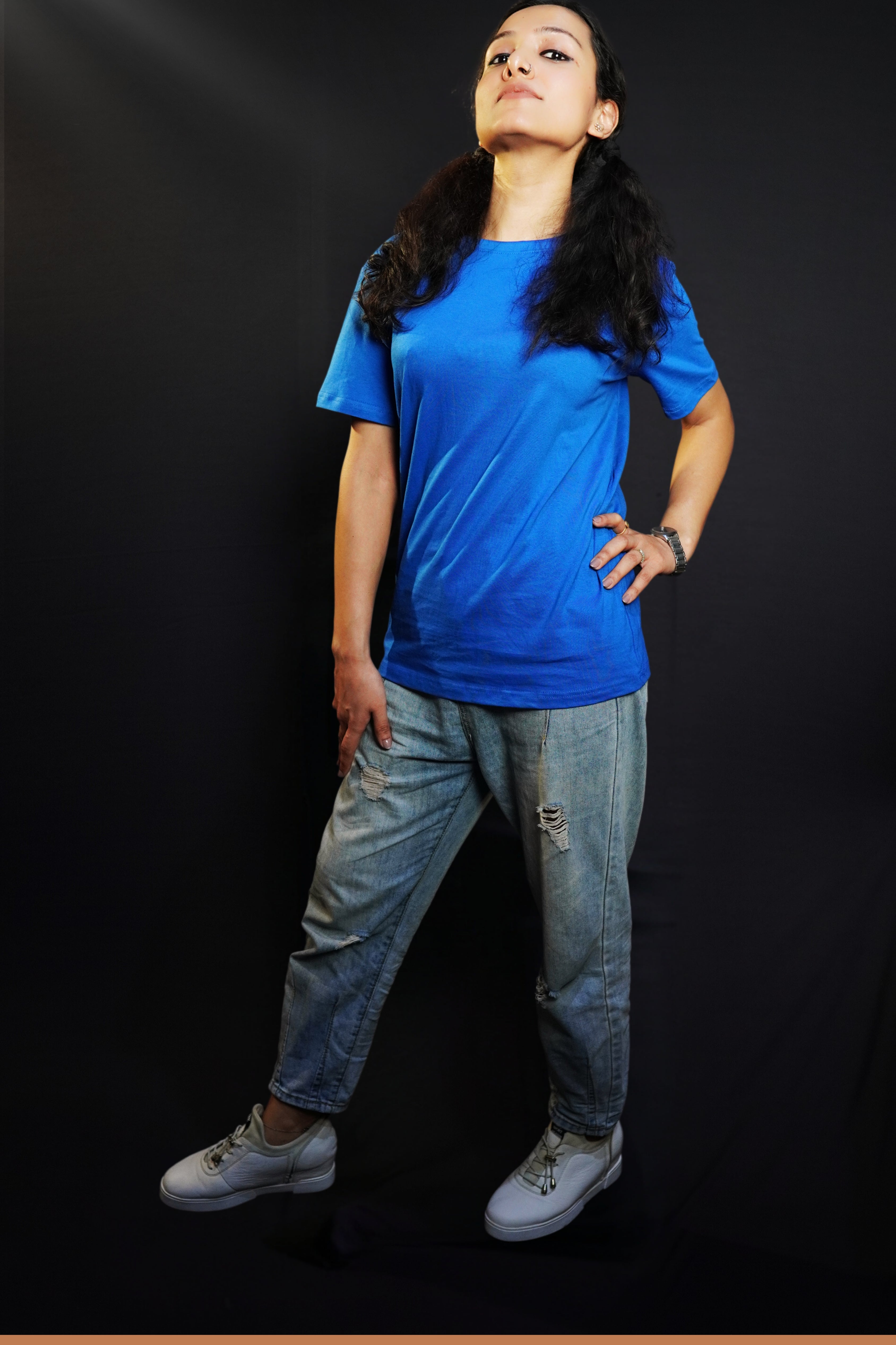 A woman with her chin high and hand on her waist and thigh, wearing a round neck quick drying summer cotton royal blue t-shirt, highlighting a trendy informal fit-Muselot