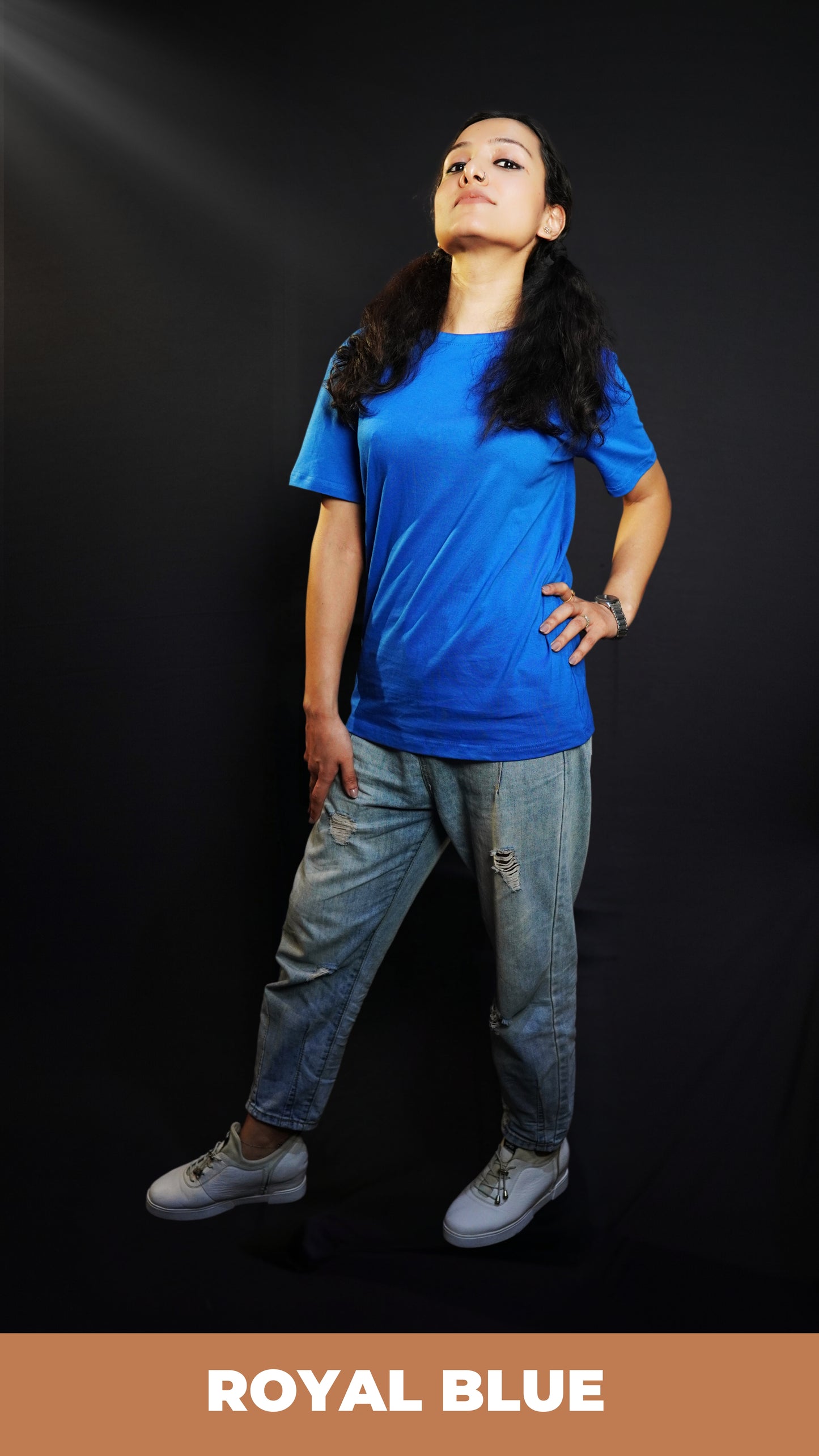 A woman with her chin high and hand on her waist and thigh, wearing a round neck quick drying summer cotton royal blue t-shirt, highlighting a trendy informal fit-Muselot