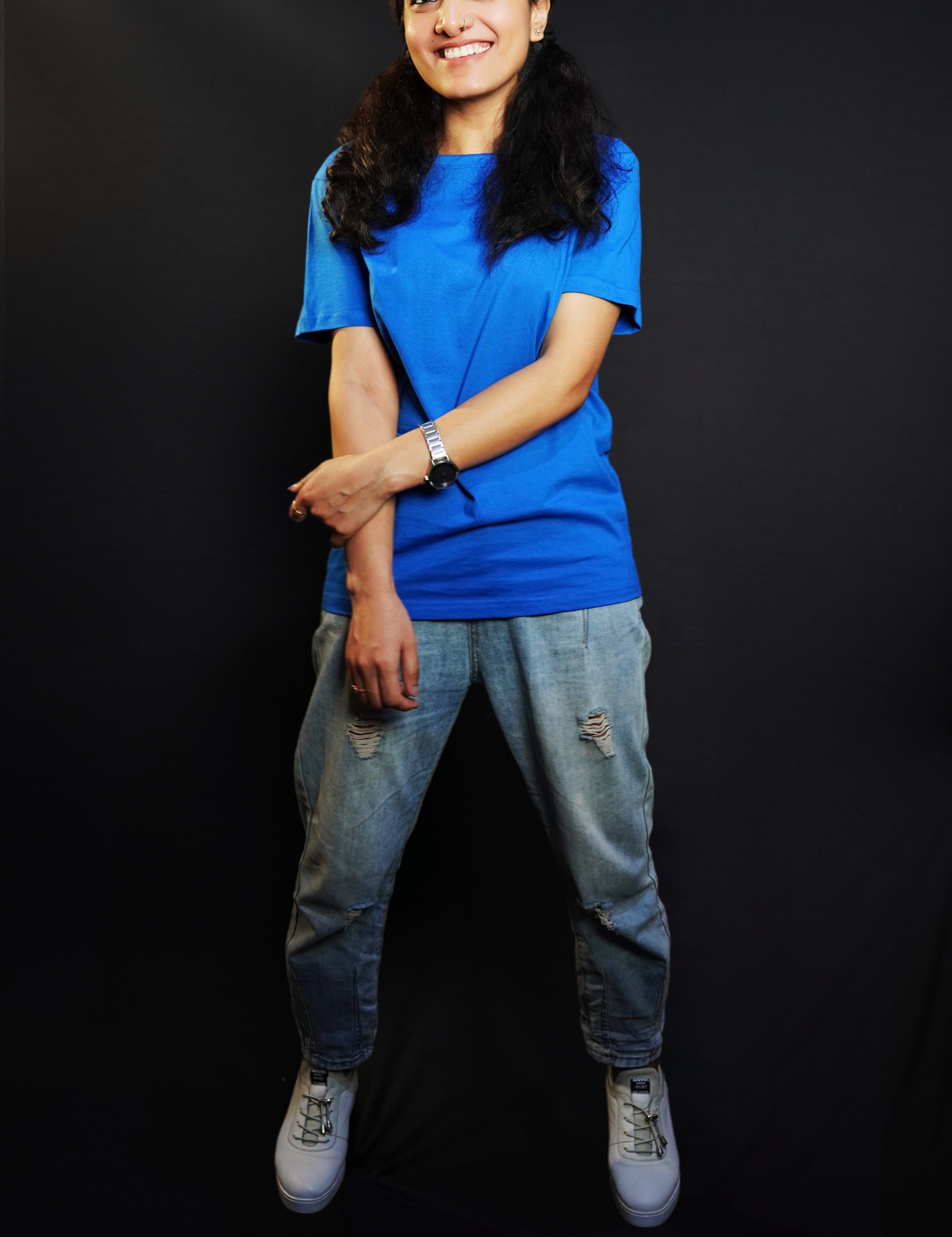 A woman laughing happily with her hand grabbing her forearm, wearing a round neck long length stretchable royal blue t-shirt, showcasing a trendy modern look-Muselot