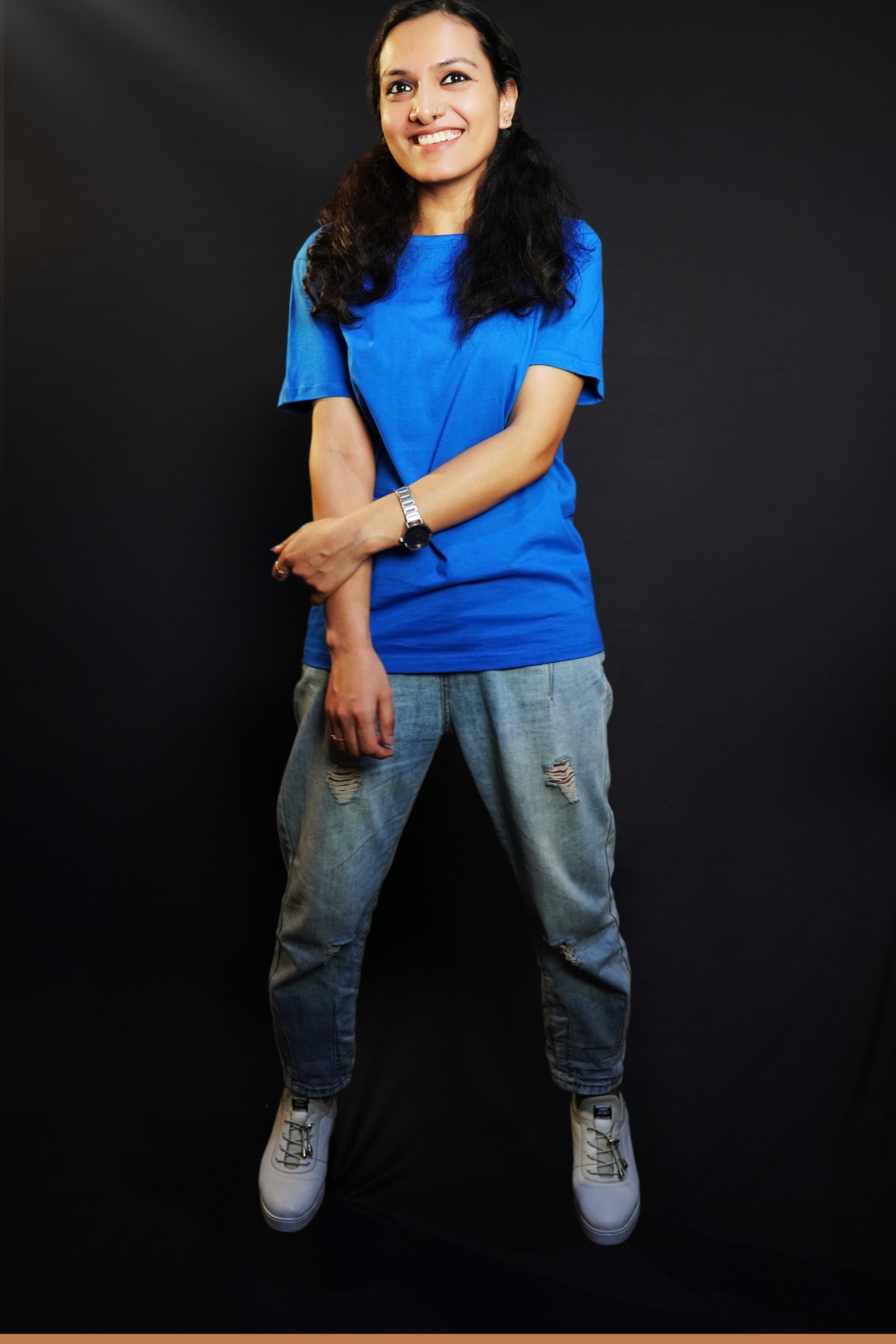 A woman laughing happily with her hand grabbing her forearm, wearing a round neck long length stretchable royal blue t-shirt, showcasing a trendy modern look-Muselot