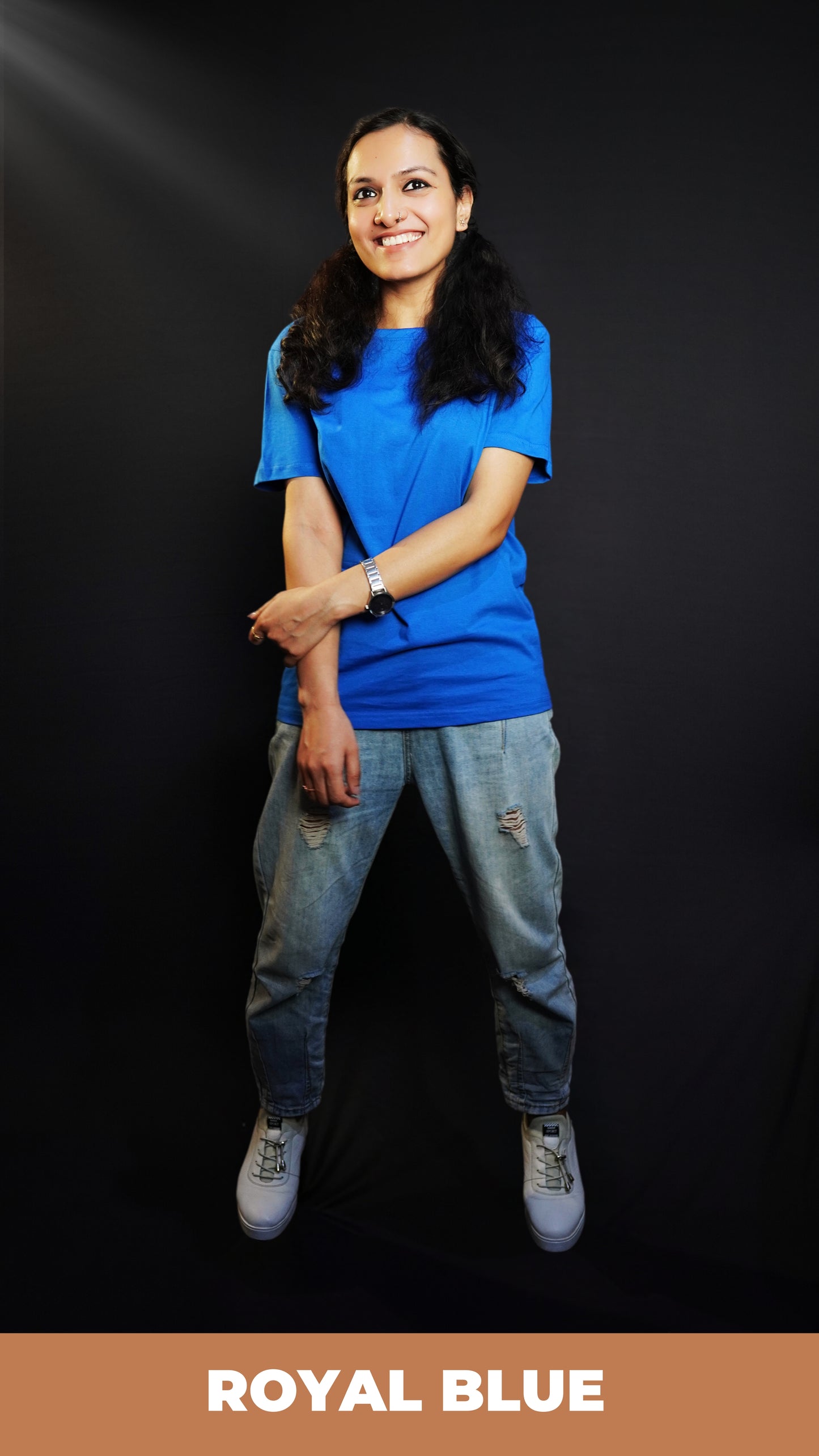 A woman laughing happily with her hand grabbing her forearm, wearing a round neck long length stretchable royal blue t-shirt, showcasing a trendy modern look-Muselot