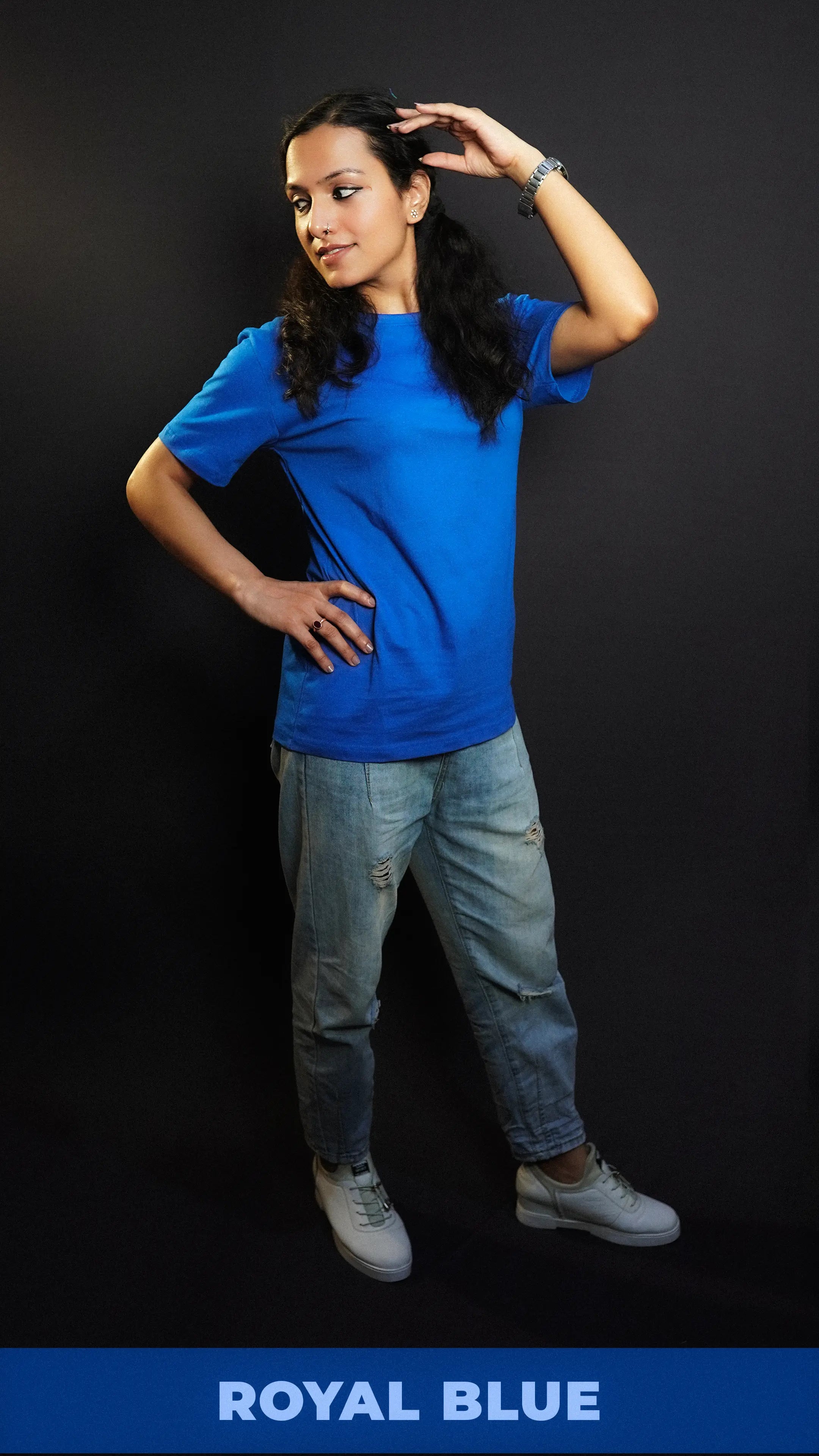 A woman wearing a unisex plain cotton round neck royal blue t-shirt, posing with her hand on her head and another on her waist as she looks sideways, highlighting a summer casual fit-Muselot
