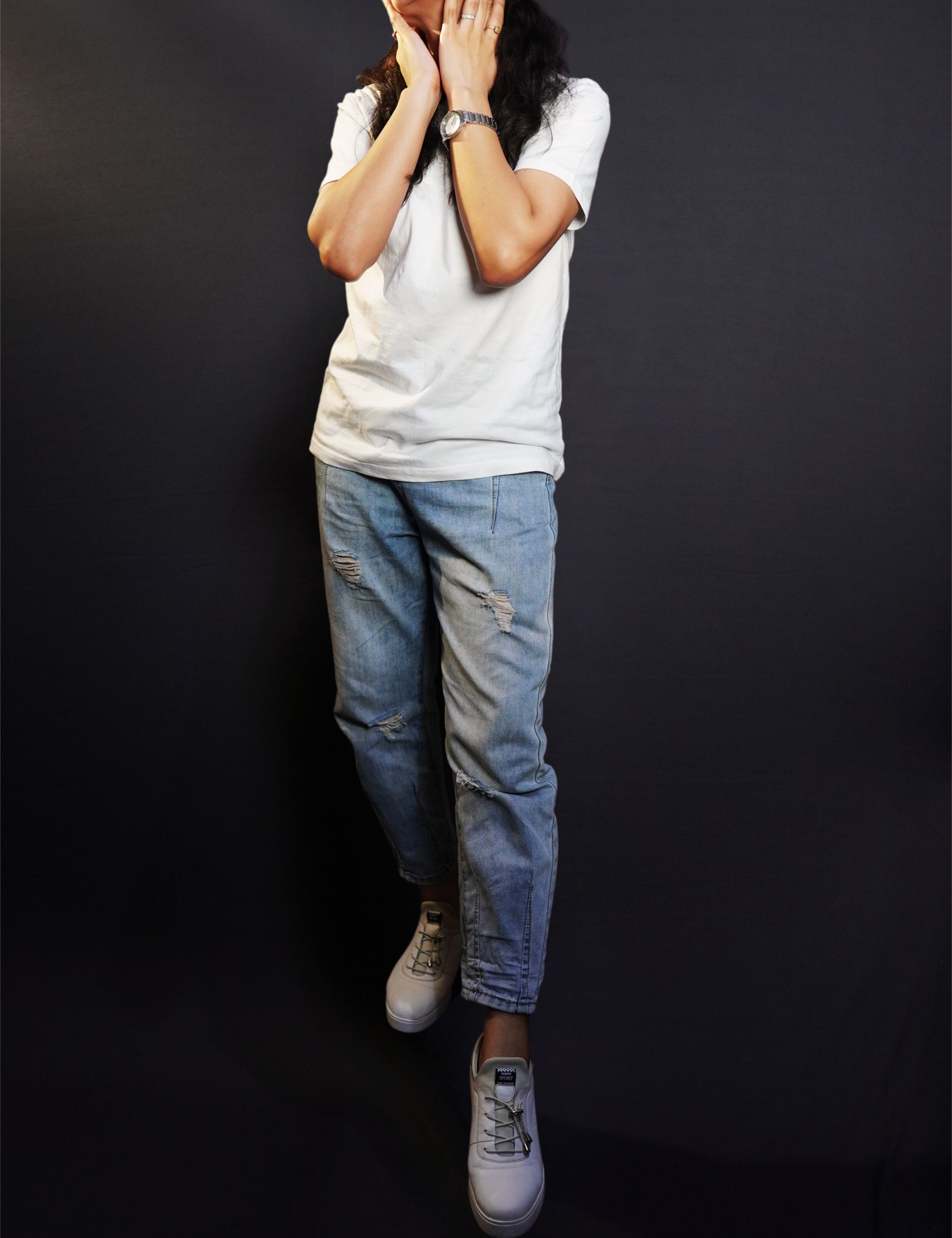 A stylish model posing with her hands on her neck, smiling happily, wearing a unisex plain snowy white round neck t-shirt, showcasing an elegant modern look-Muselot