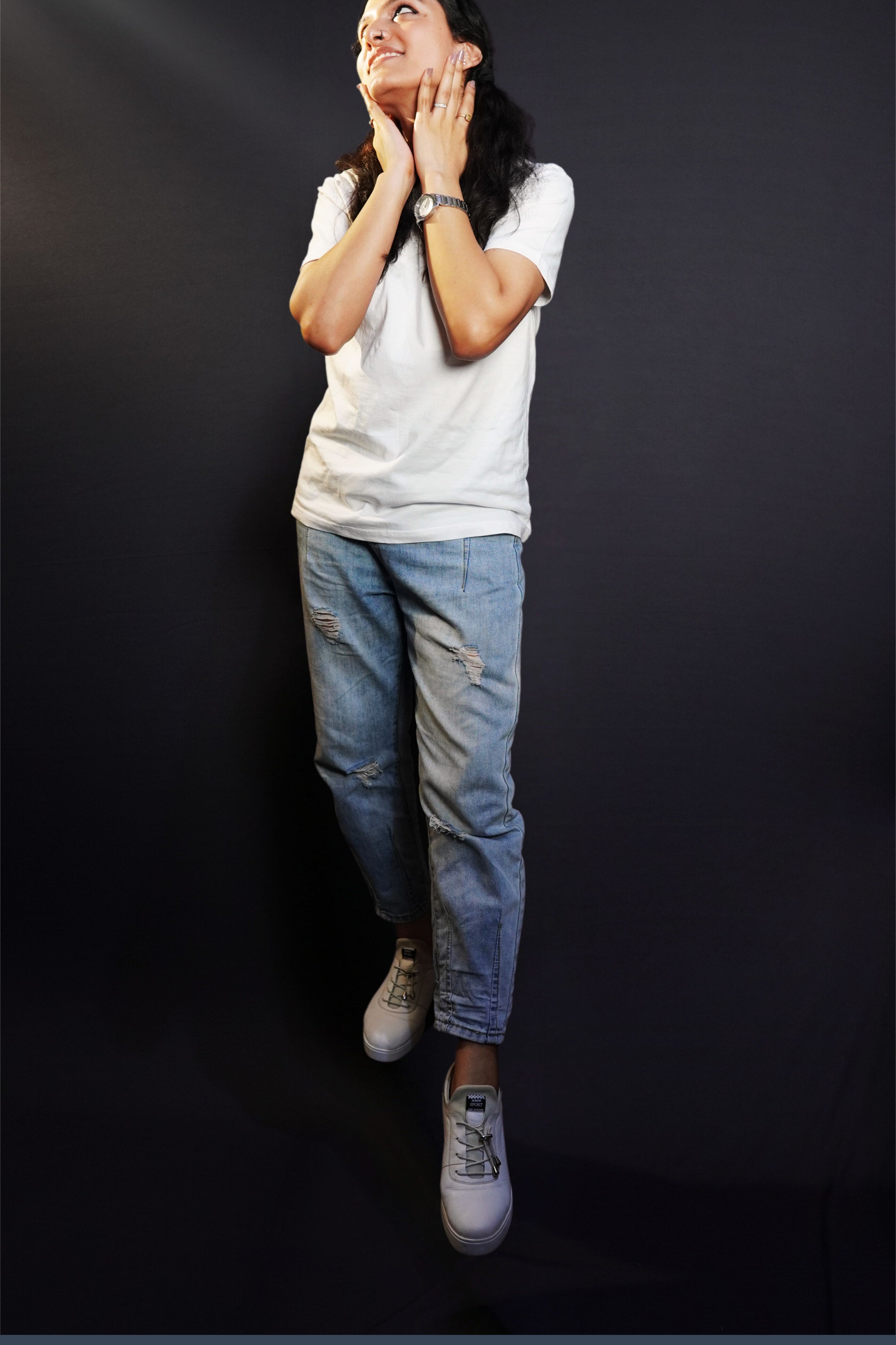 A stylish model posing with her hands on her neck, smiling happily, wearing a unisex plain snowy white round neck t-shirt, showcasing an elegant modern look-Muselot