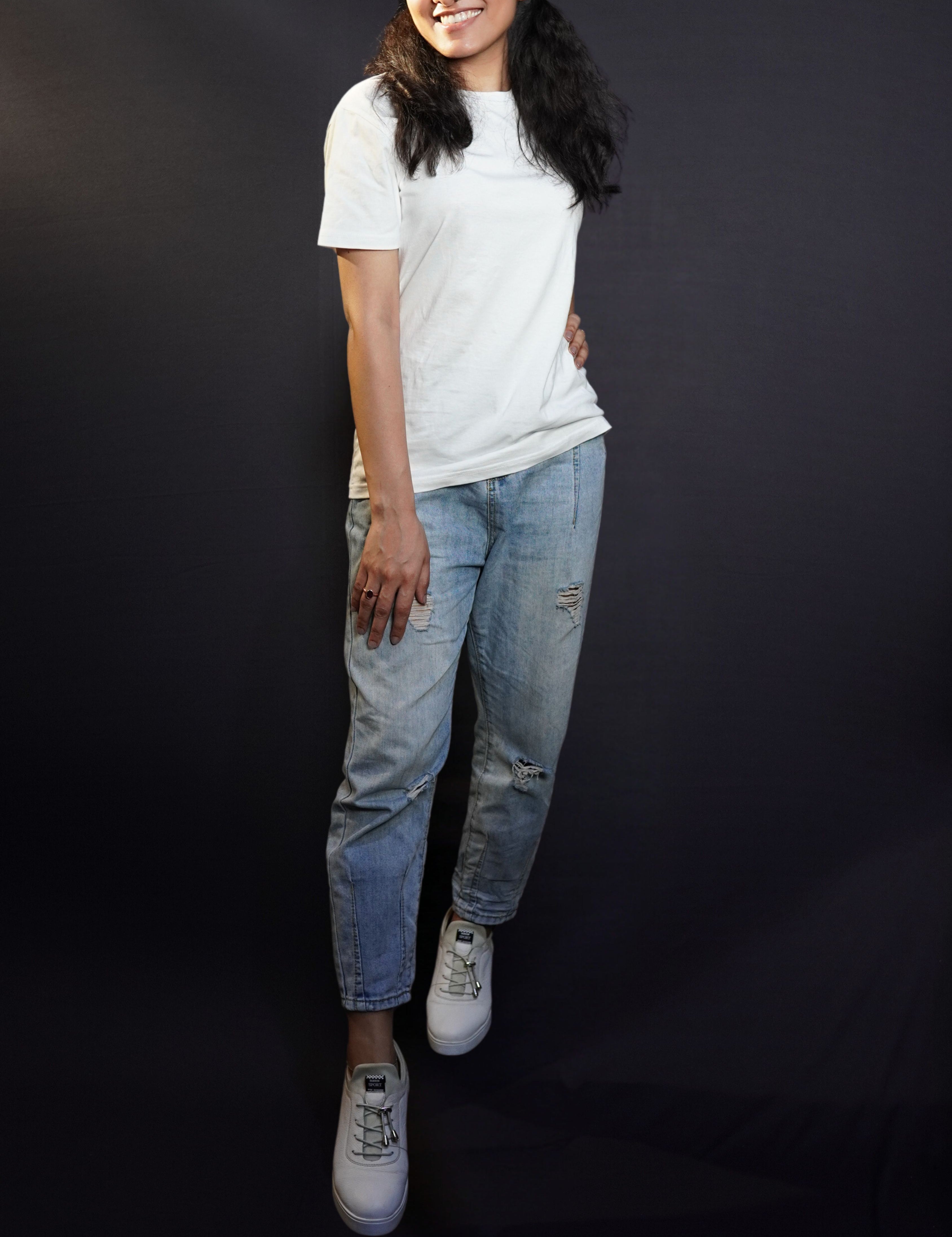 A woman smiling brightly posing with her hand on her thigh, standing sideway with another hand on her waist, wearing a women's summer short sleeved snowy white t-shirt, showcasing a comfortable snug fit-Muselot
