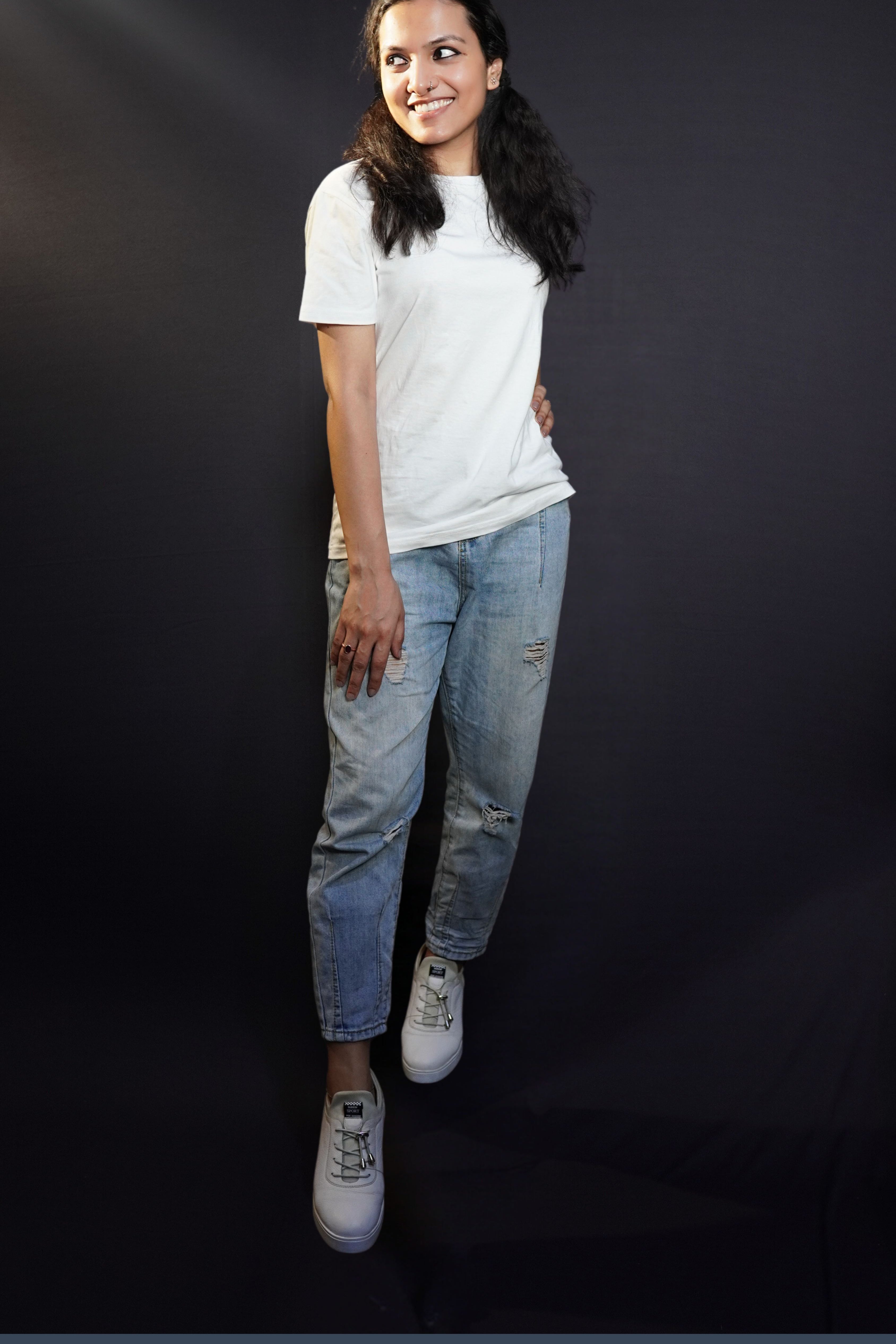 A woman smiling brightly posing with her hand on her thigh, standing sideway with another hand on her waist, wearing a women's summer short sleeved snowy white t-shirt, showcasing a comfortable snug fit-Muselot