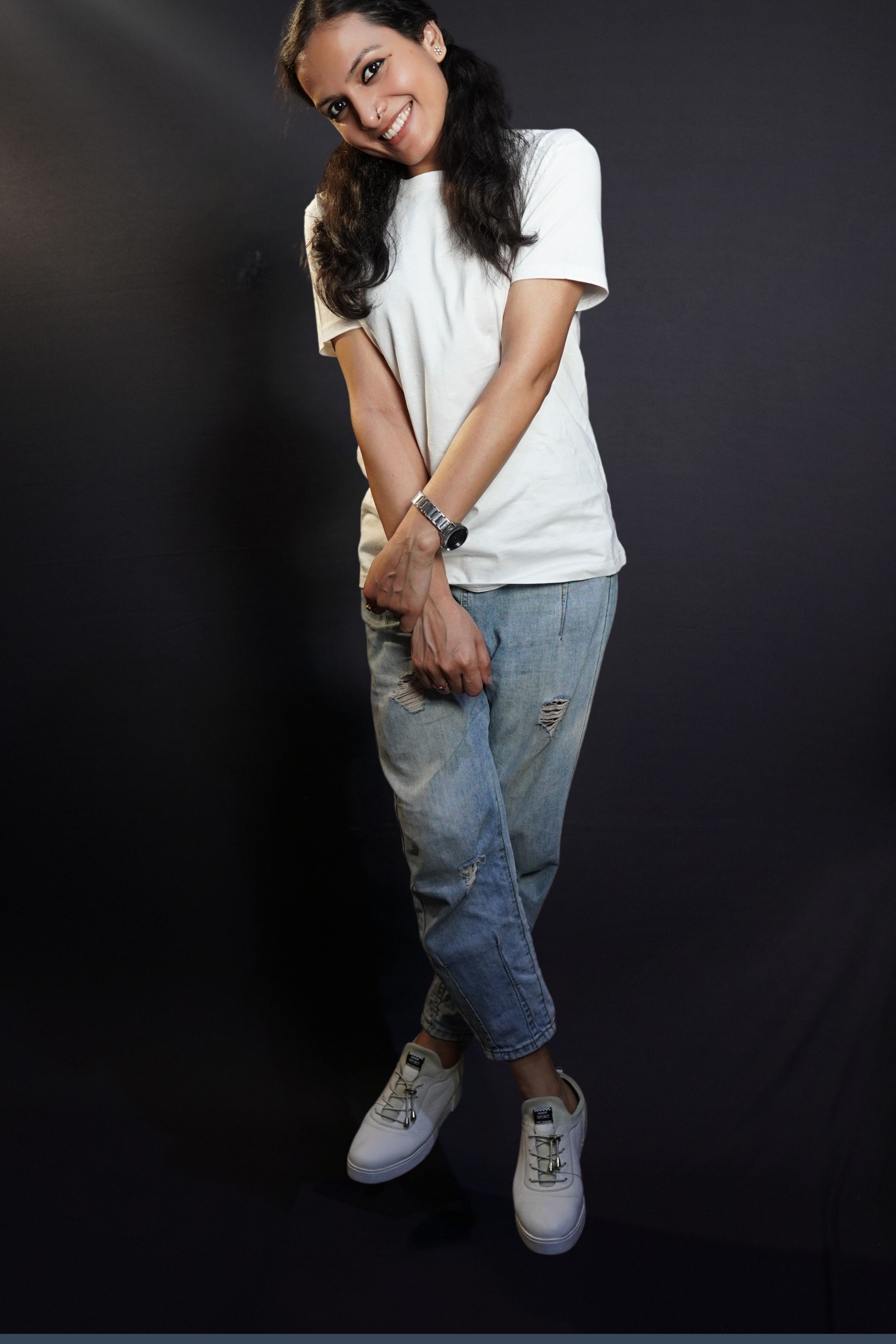A woman wearing a plain plus size men's snowy white round neck t-shirt, posing with her hand grabbing the wrist of the other, smiling brightly, highlighting a trendy baggy fit-Muselot