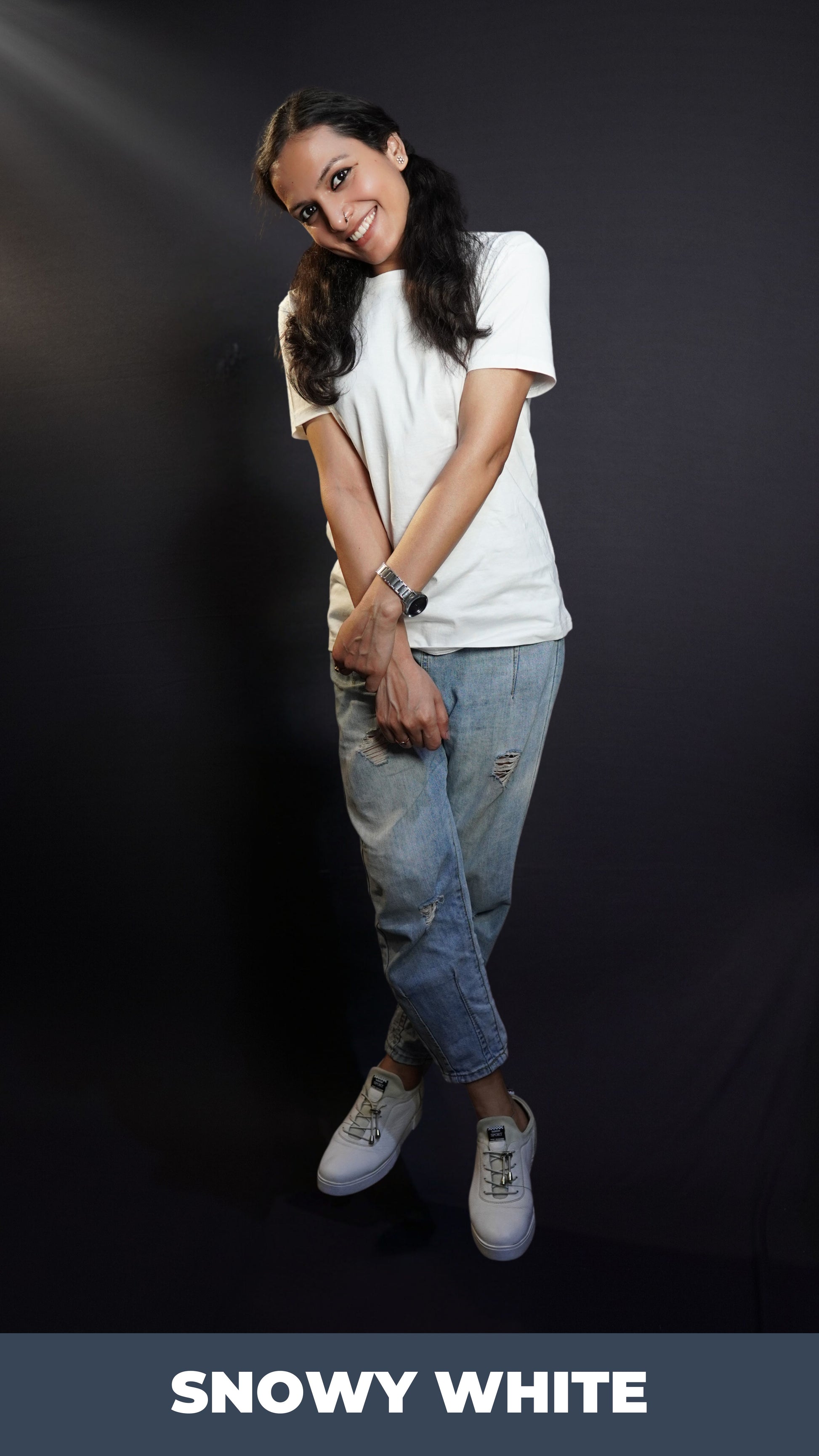 A woman wearing a plain plus size men's snowy white round neck t-shirt, posing with her hand grabbing the wrist of the other, smiling brightly, highlighting a trendy baggy fit-Muselot