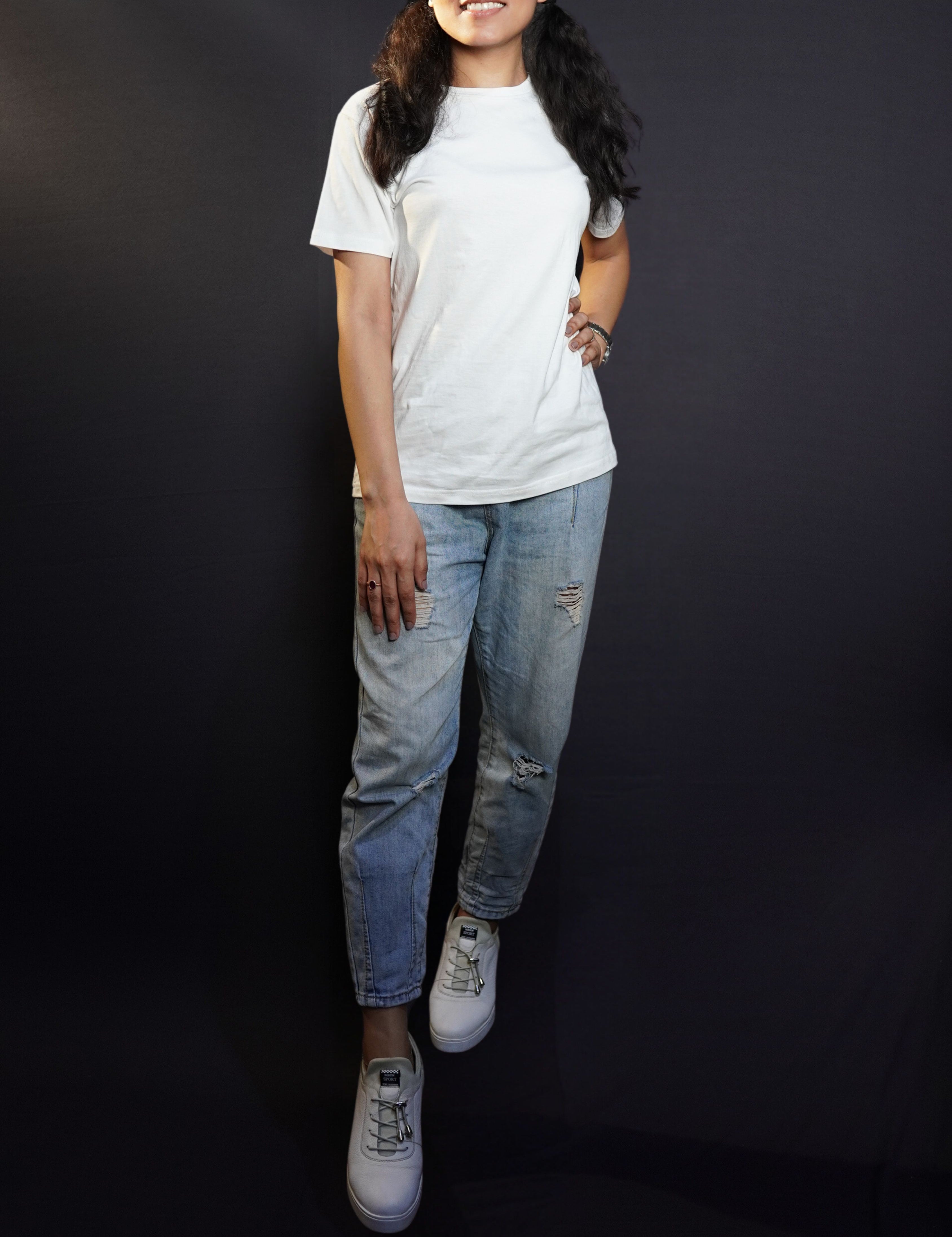 A stylish model posing with her hand on her waist and another on her thigh looking directly at the camera, wearing an adult's summer long length stretchable snowy white t-shirt, showcasing an elegant informal look-Muselot