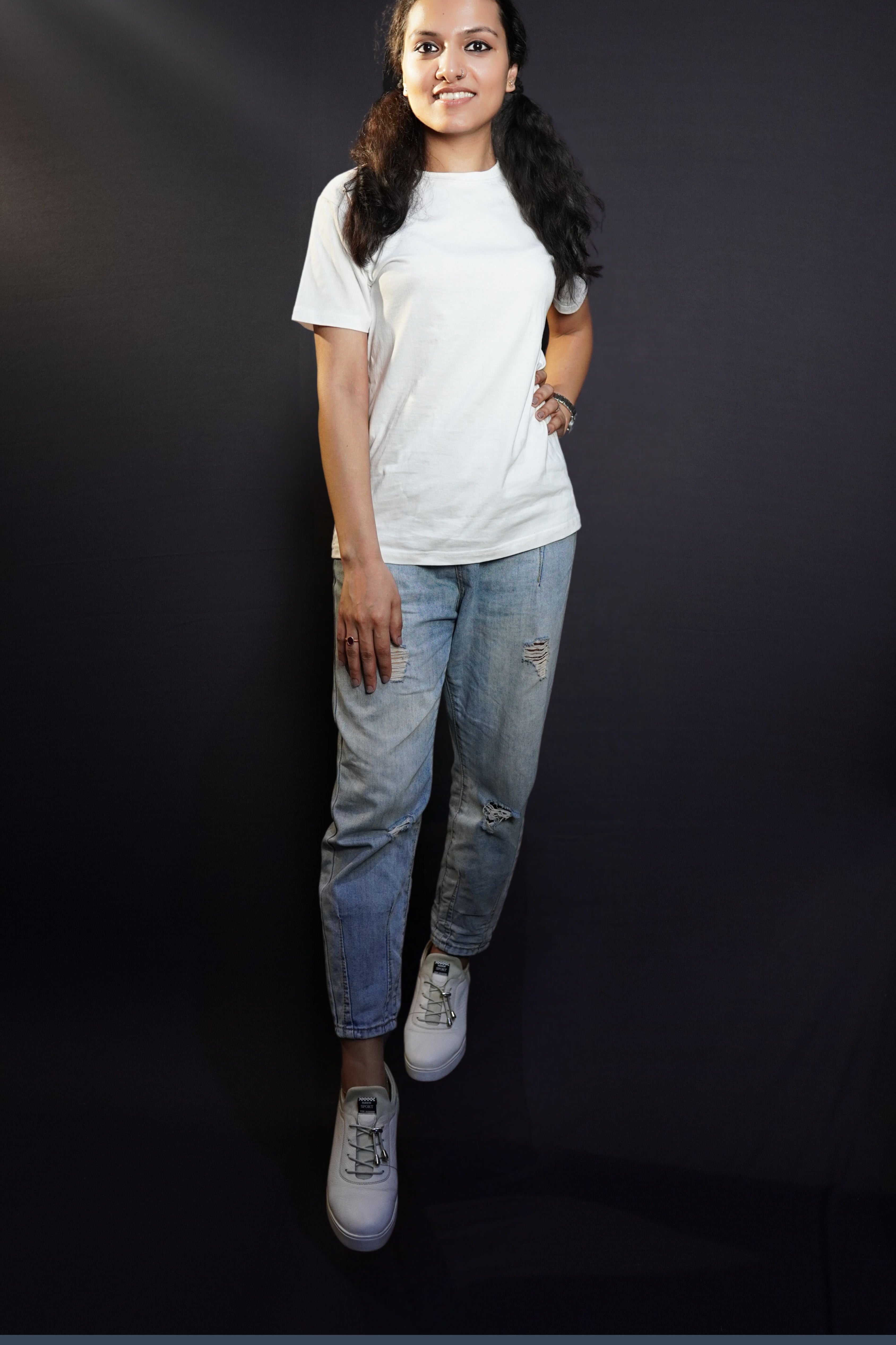 A stylish model posing with her hand on her waist and another on her thigh looking directly at the camera, wearing an adult's summer long length stretchable snowy white t-shirt, showcasing an elegant informal look-Muselot