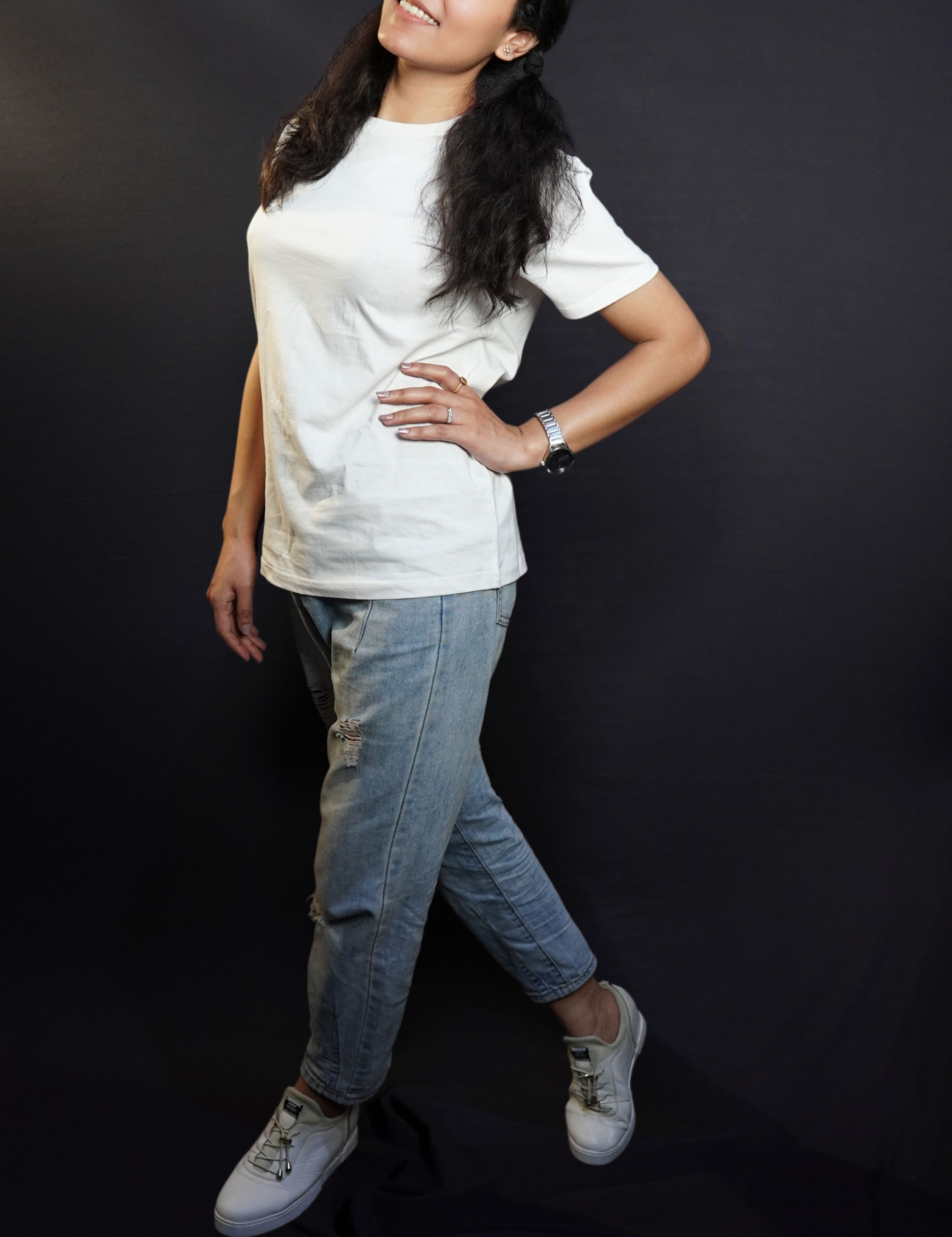A woman wearing a moisture wicking cotton round neck snowy white girl's t-shirt, posing with her hand on her waist and another hanging on her side as she stands sideways, highlighting a casual everyday look-Muselot