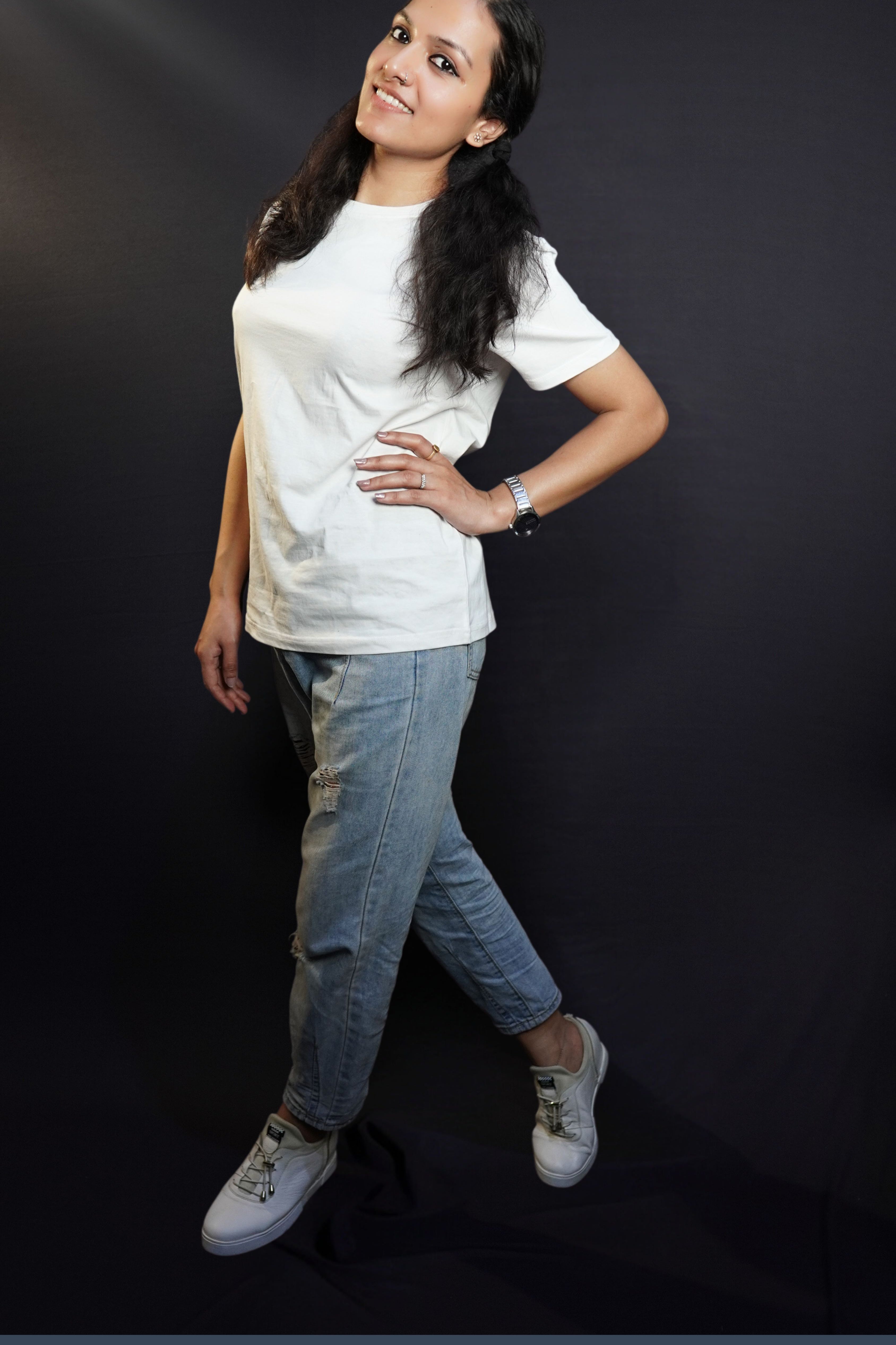 A woman wearing a moisture wicking cotton round neck snowy white girl's t-shirt, posing with her hand on her waist and another hanging on her side as she stands sideways, highlighting a casual everyday look-Muselot