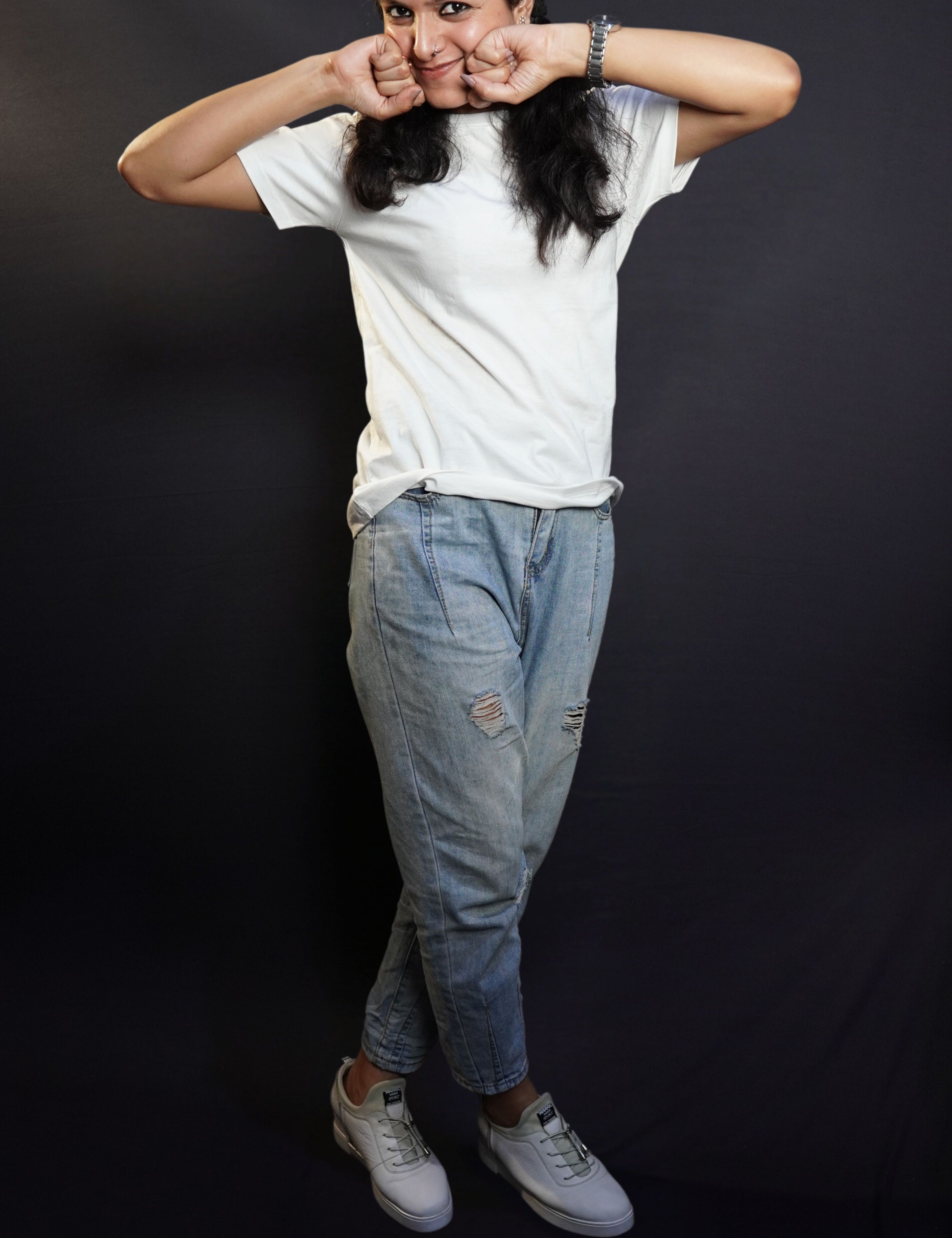 A woman happily posing with her fists on her cheeks and a sweet smile on her lips, wearing a snowy white plain long length quick drying t-shirt, highlighting a relaxed cozy fit-Muselot