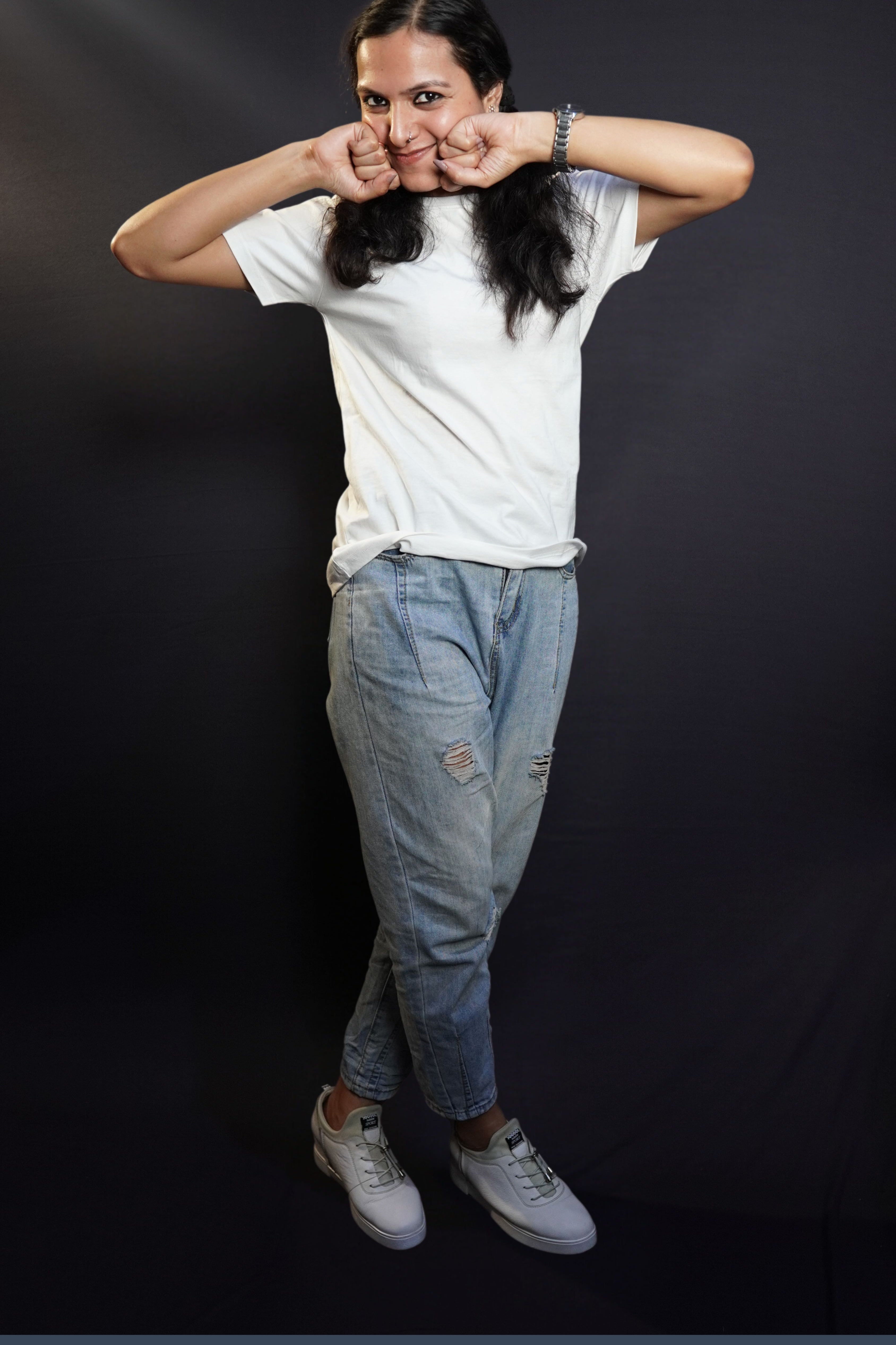 A woman happily posing with her fists on her cheeks and a sweet smile on her lips, wearing a snowy white plain long length quick drying t-shirt, highlighting a relaxed cozy fit-Muselot