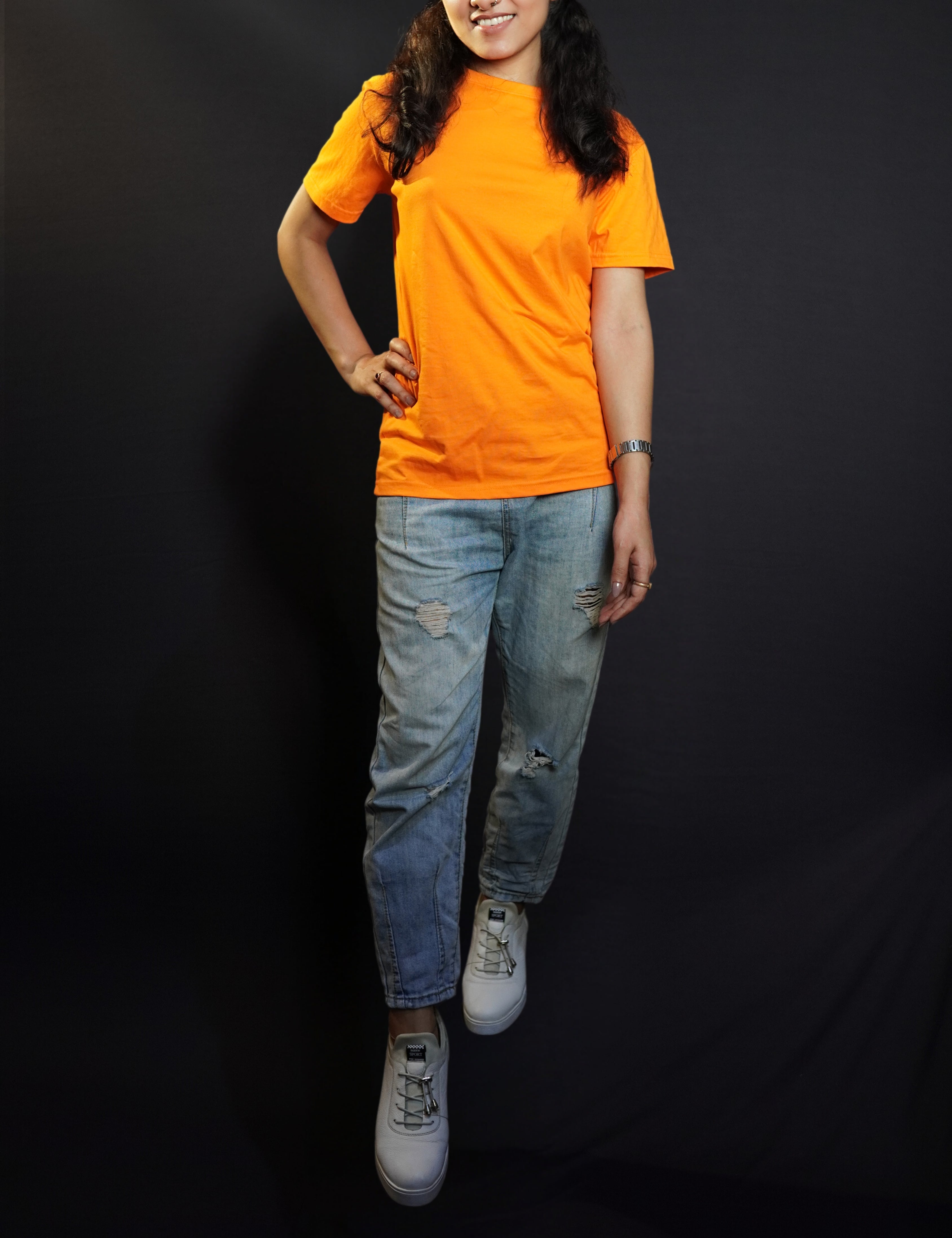 A stylish model posing with her hand on her waist and one leg forward, smiling happily, wearing a round neck cotton summer moisture wicking tropical orange t-shirt, showcasing a stylish in demand look-Muselot