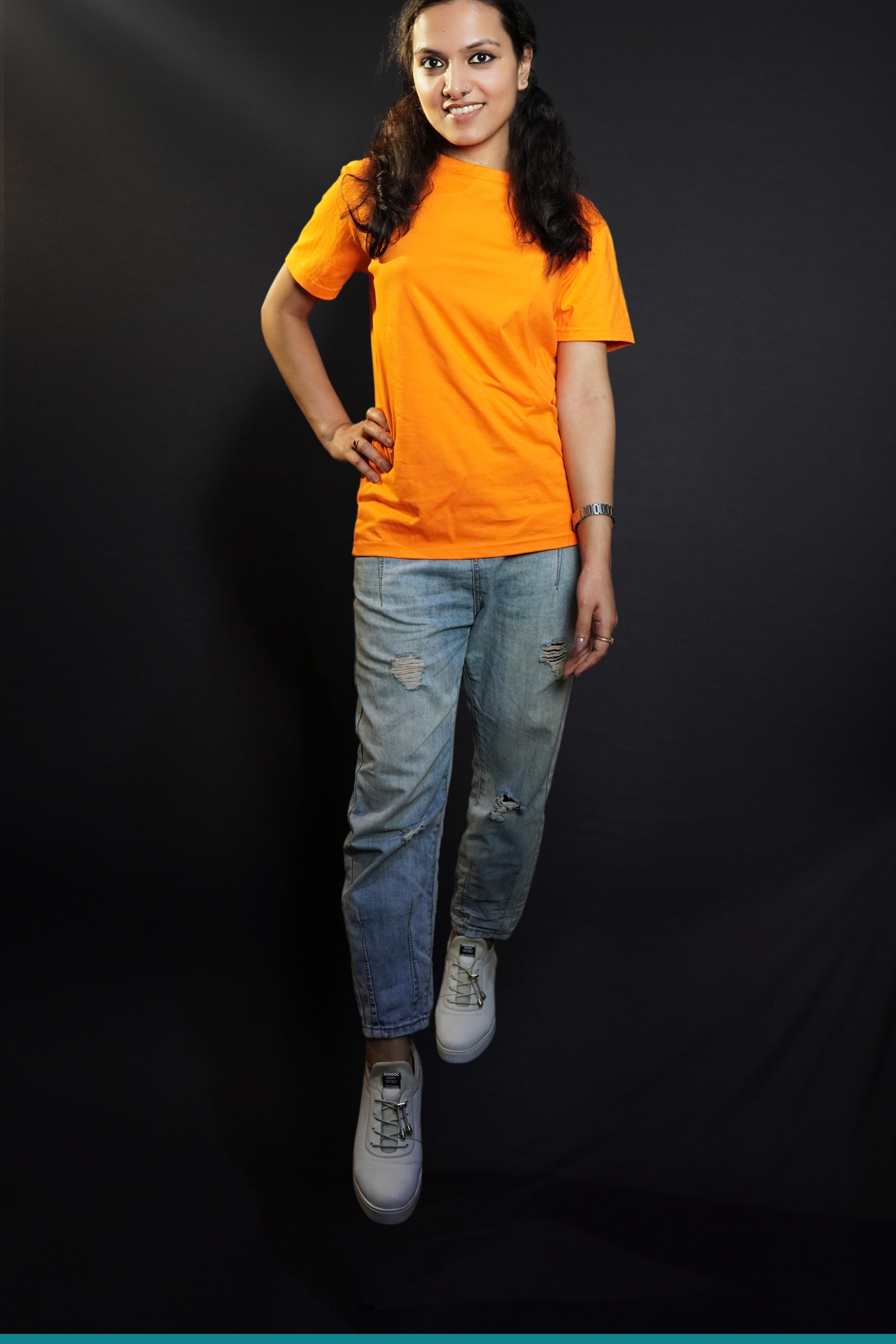 A stylish model posing with her hand on her waist and one leg forward, smiling happily, wearing a round neck cotton summer moisture wicking tropical orange t-shirt, showcasing a stylish in demand look-Muselot