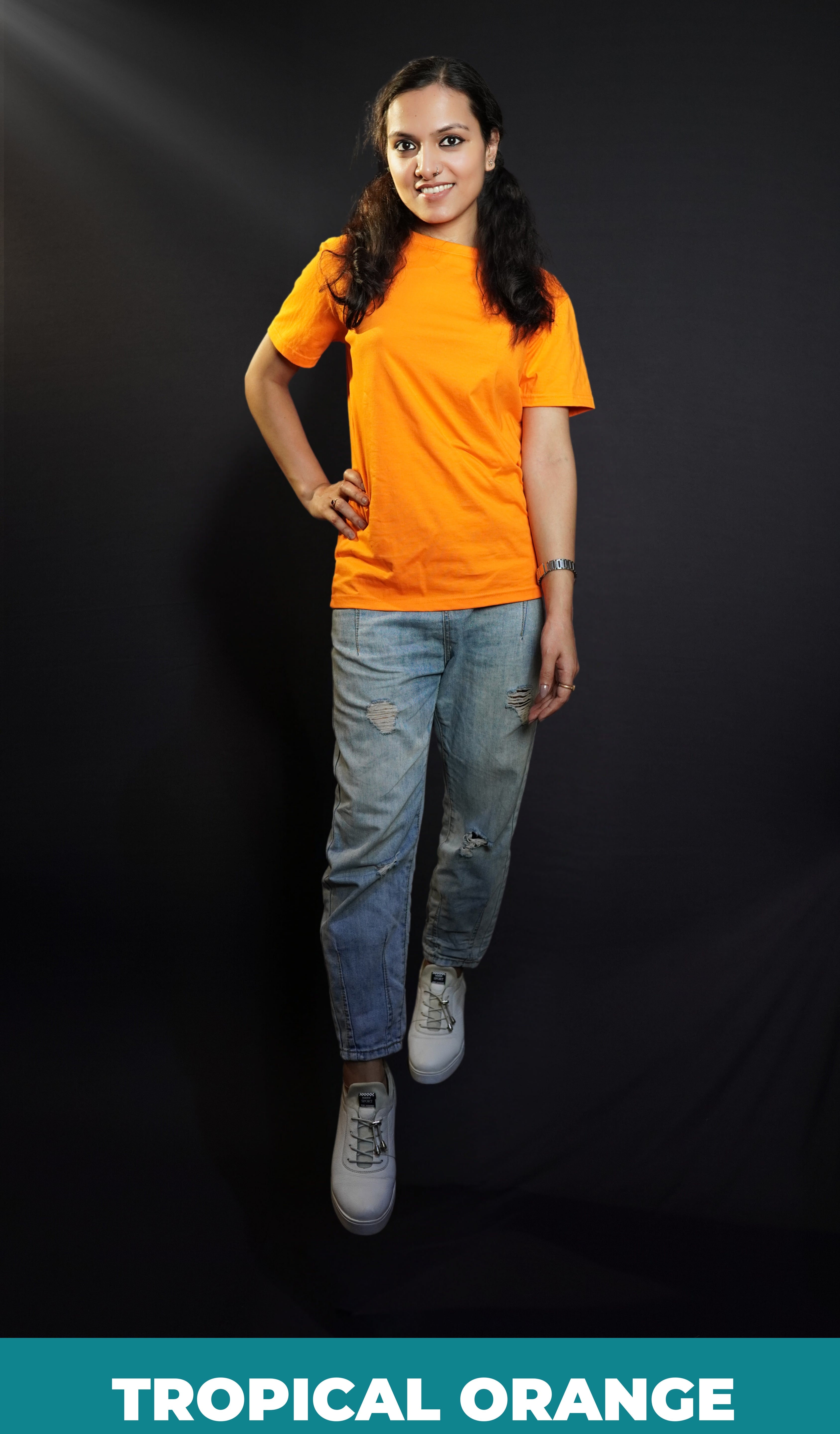 A stylish model posing with her hand on her waist and one leg forward, smiling happily, wearing a round neck cotton summer moisture wicking tropical orange t-shirt, showcasing a stylish in demand look-Muselot