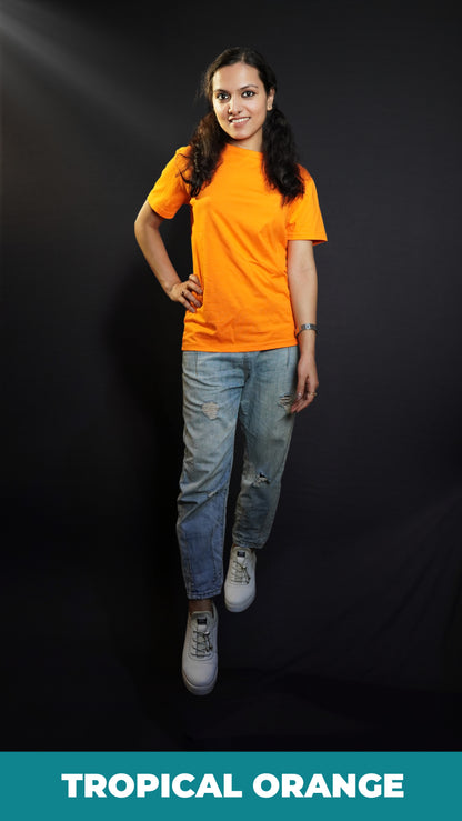 A stylish model posing with her hand on her waist and one leg forward, smiling happily, wearing a round neck cotton summer moisture wicking tropical orange t-shirt, showcasing a stylish in demand look-Muselot