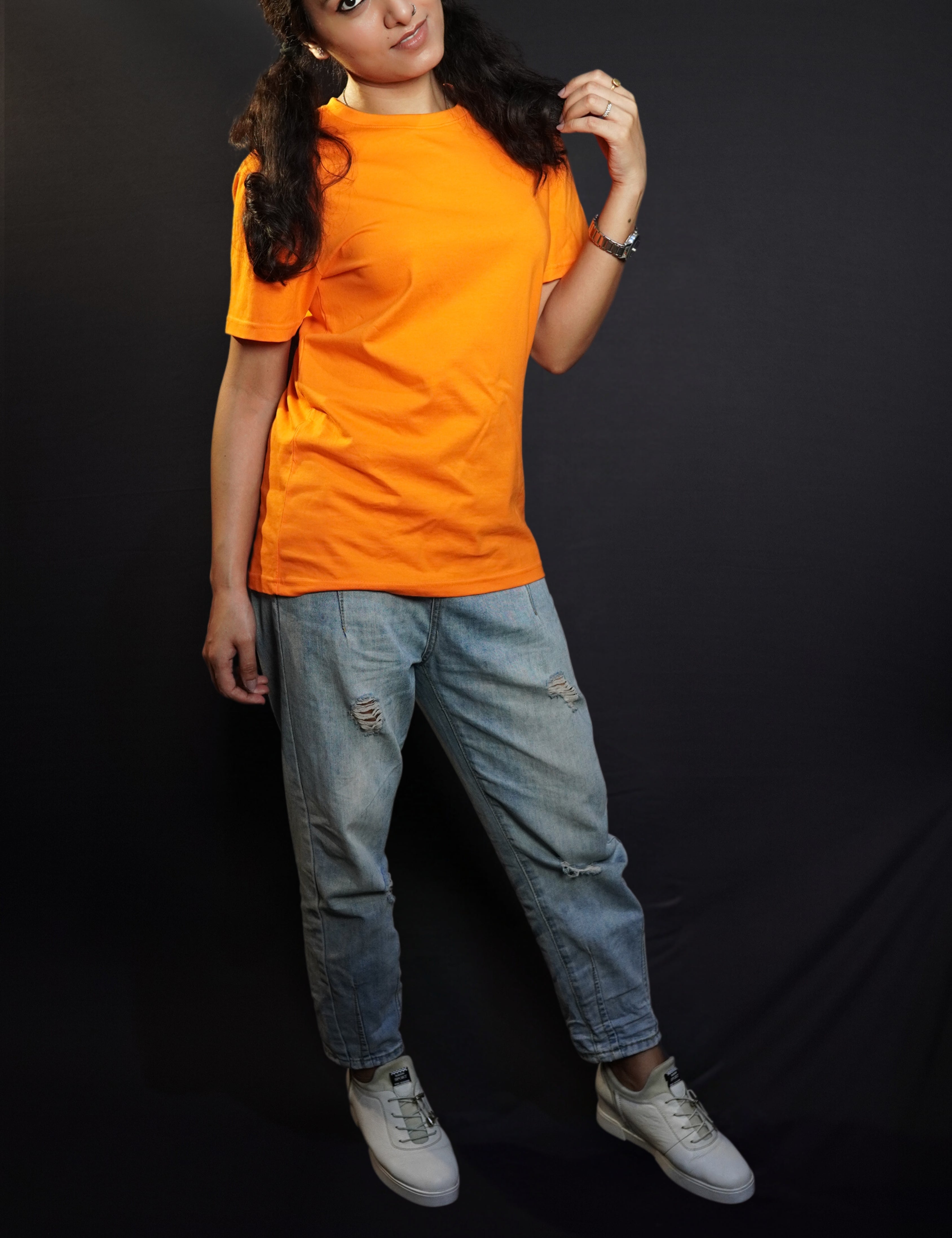 A woman wearing a plain round neck unisex tropical orange t-shirt, posing with her hand gently grazing her hair, smiling with her eyes, showcasing a stylish pretty look-Muselot