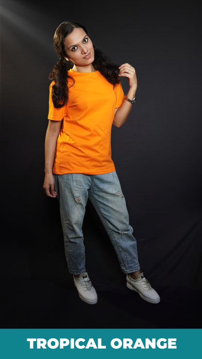 A woman wearing a plain round neck unisex tropical orange t-shirt, posing with her hand gently grazing her hair, smiling with her eyes, showcasing a stylish pretty look-Muselot