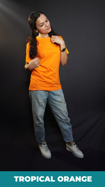 A model in a women's short sleeved summer tropical orange t-shirt, posing with hand grabbing a section of her short her and other just grabbing of the tip of other section on her shoulder, bending her head slightly, showcasing a modern informal look-Muselot