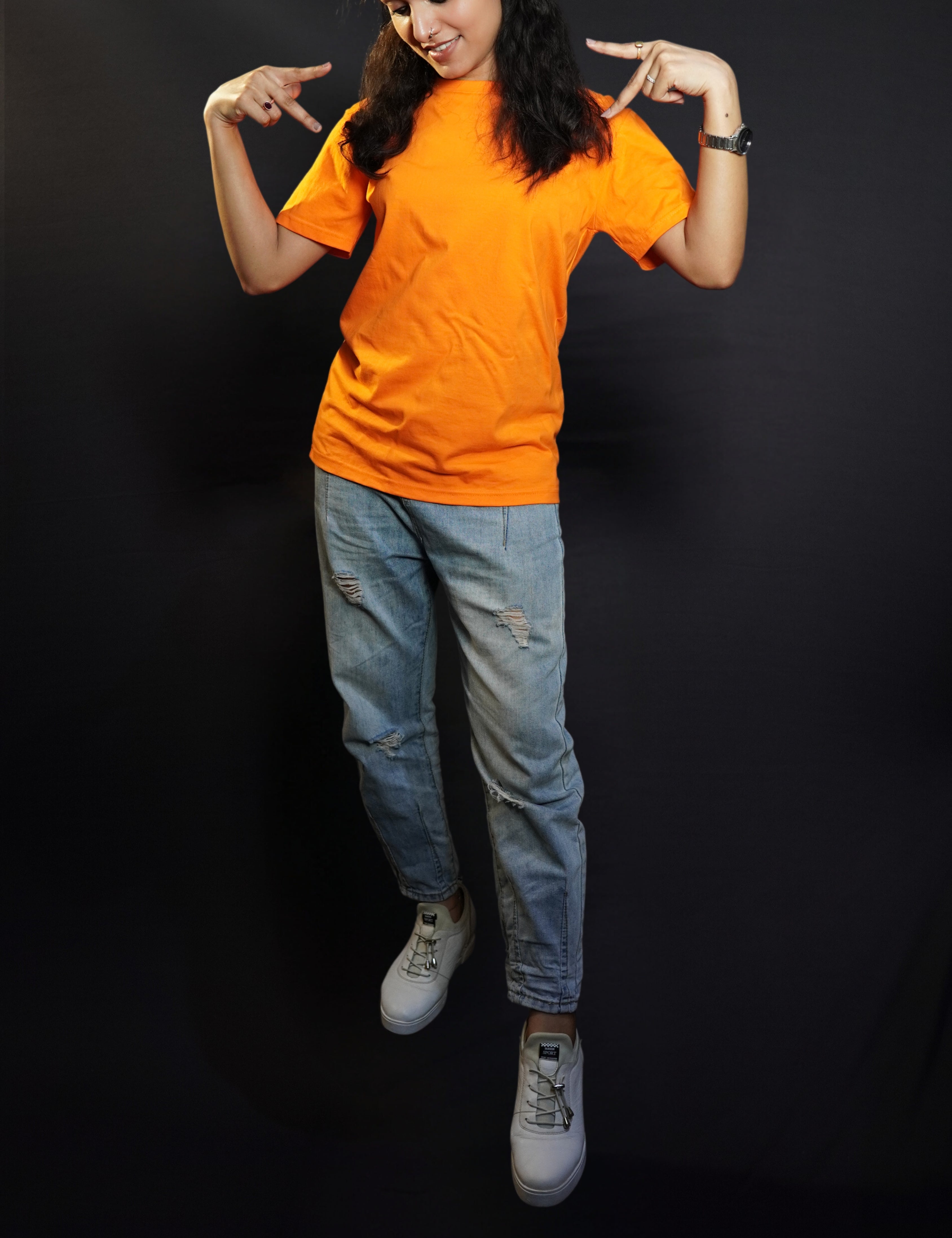 A stylish woman wearing a long length stretchable tropical orange plain extra large t-shirt, posing with her hands upon her shoulders making a v sign with her fingers, highlighting a bright everyday look-Muselot