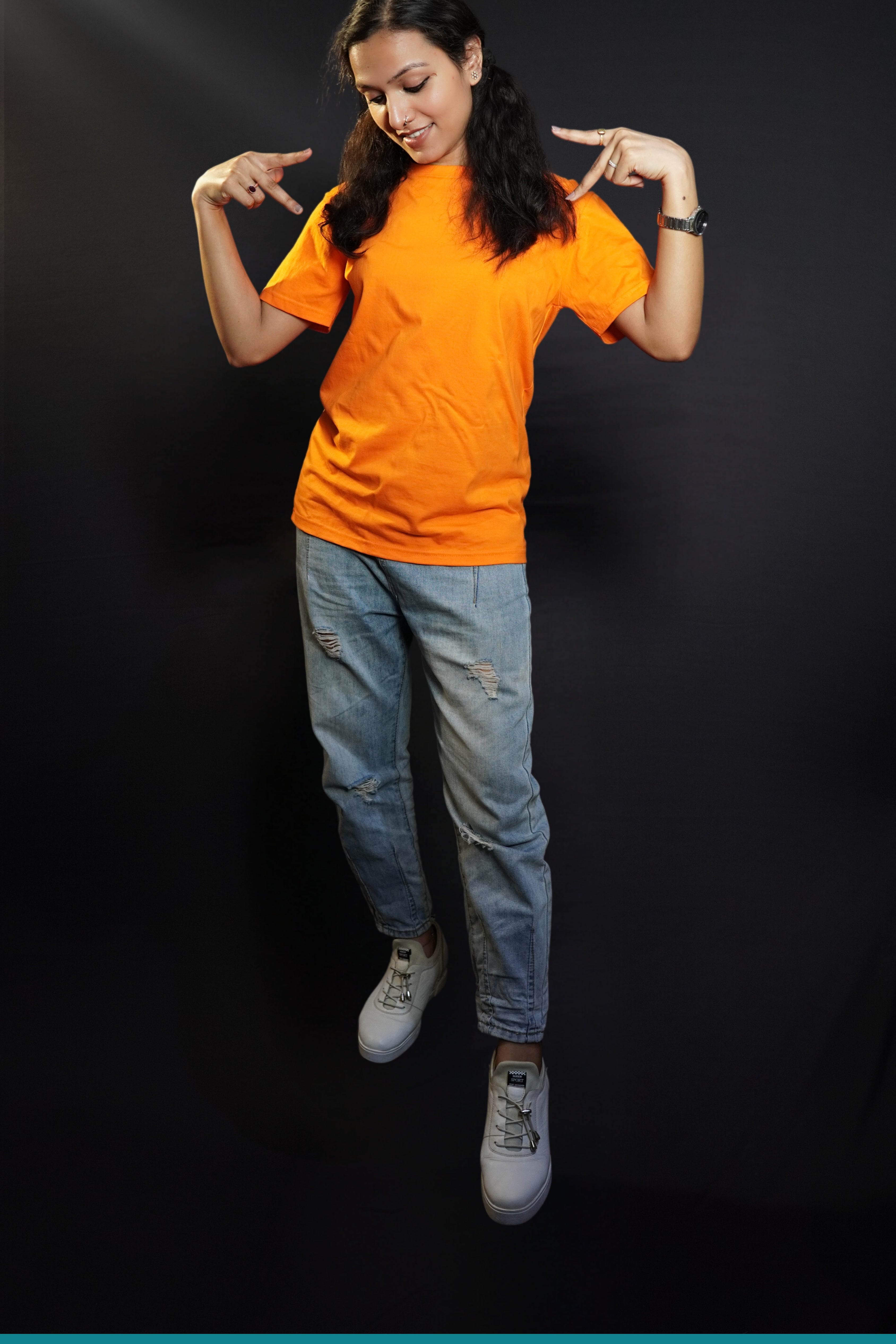 A stylish woman wearing a long length stretchable tropical orange plain extra large t-shirt, posing with her hands upon her shoulders making a v sign with her fingers, highlighting a bright everyday look-Muselot