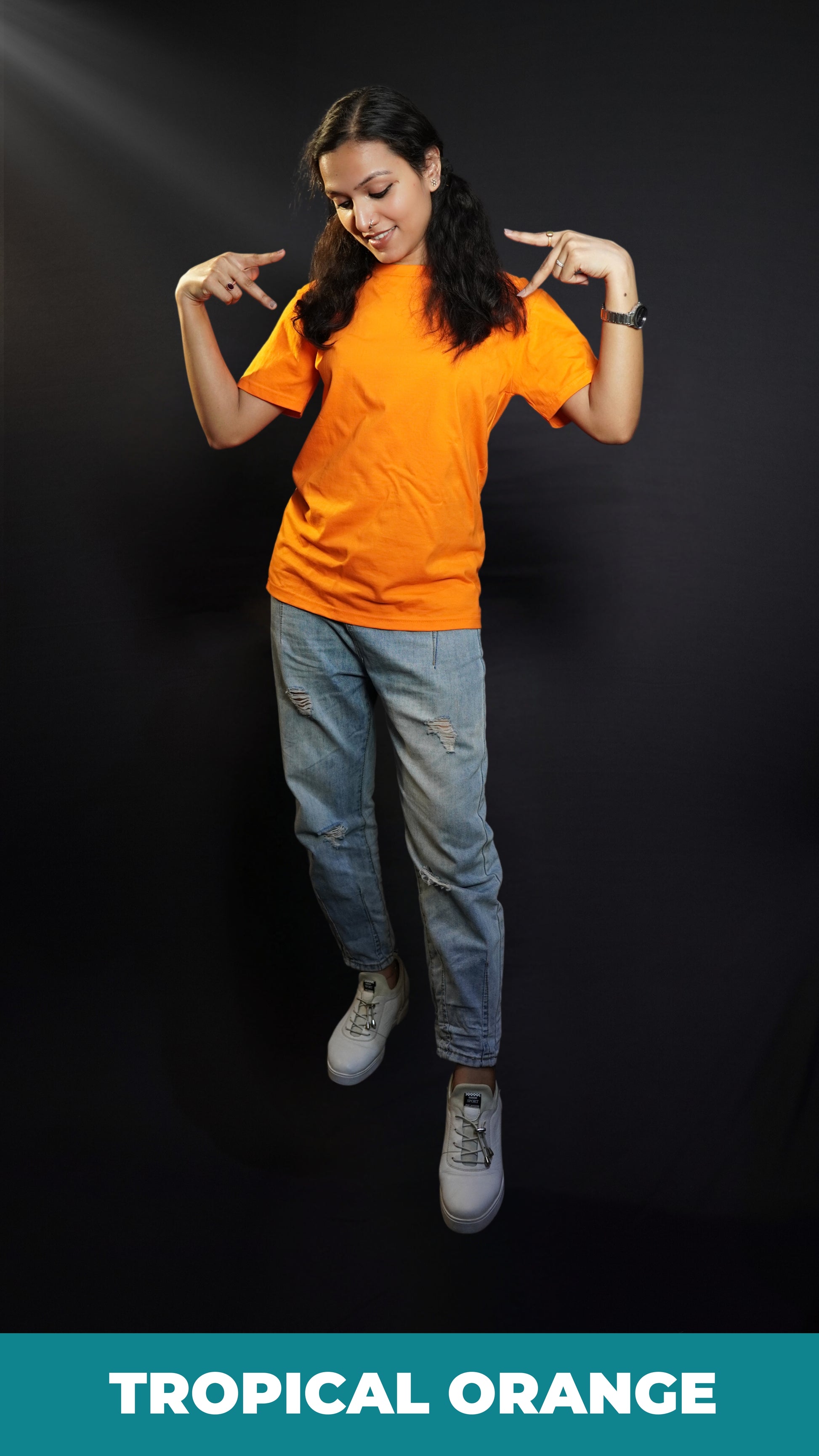 A stylish woman wearing a long length stretchable tropical orange plain extra large t-shirt, posing with her hands upon her shoulders making a v sign with her fingers, highlighting a bright everyday look-Muselot