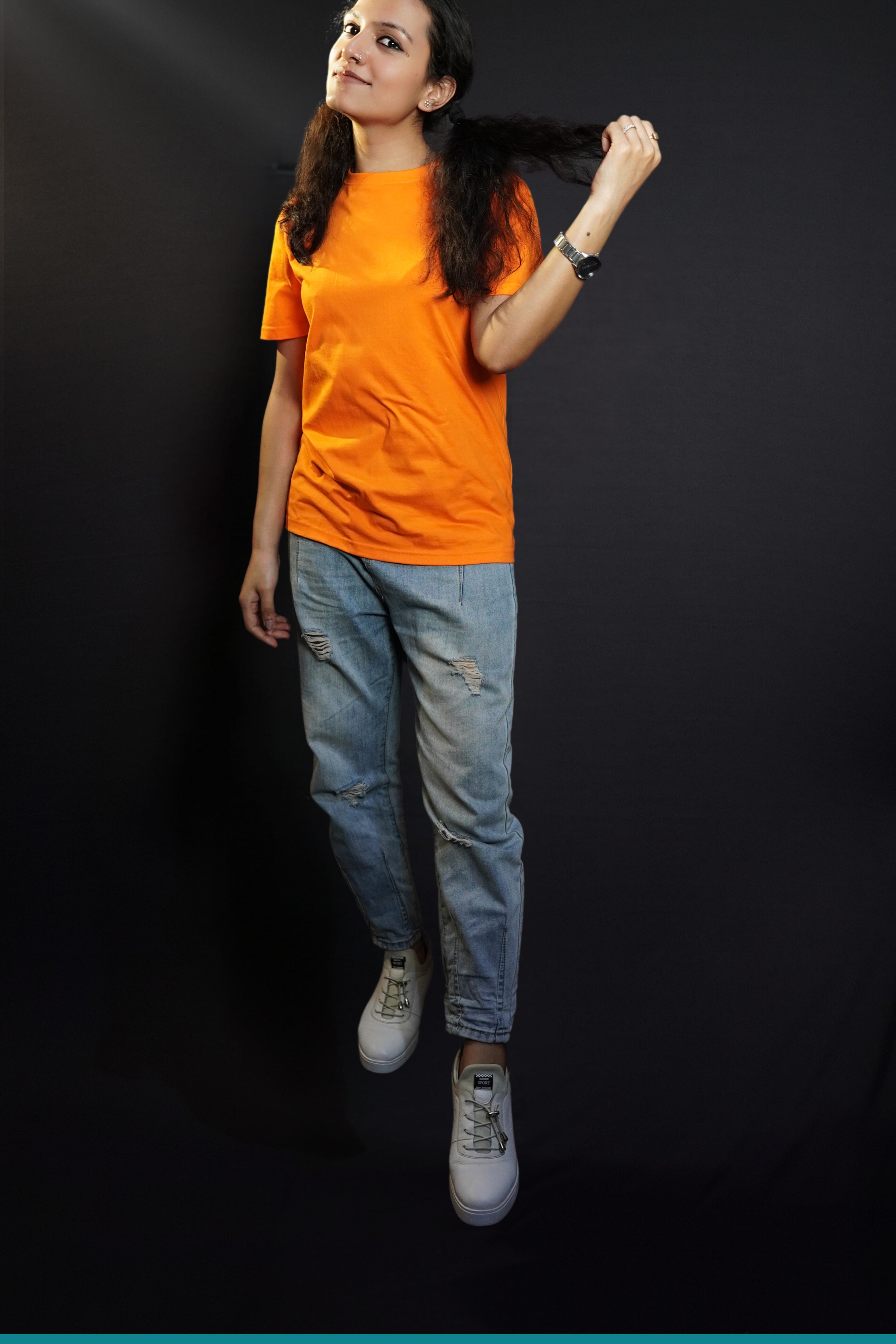 A woman wearing a long length short sleeved round neck plain cotton orange t-shirt, posing with her hand pulling a section of her short hair, showcasing a relaxed cozy fit-Muselot