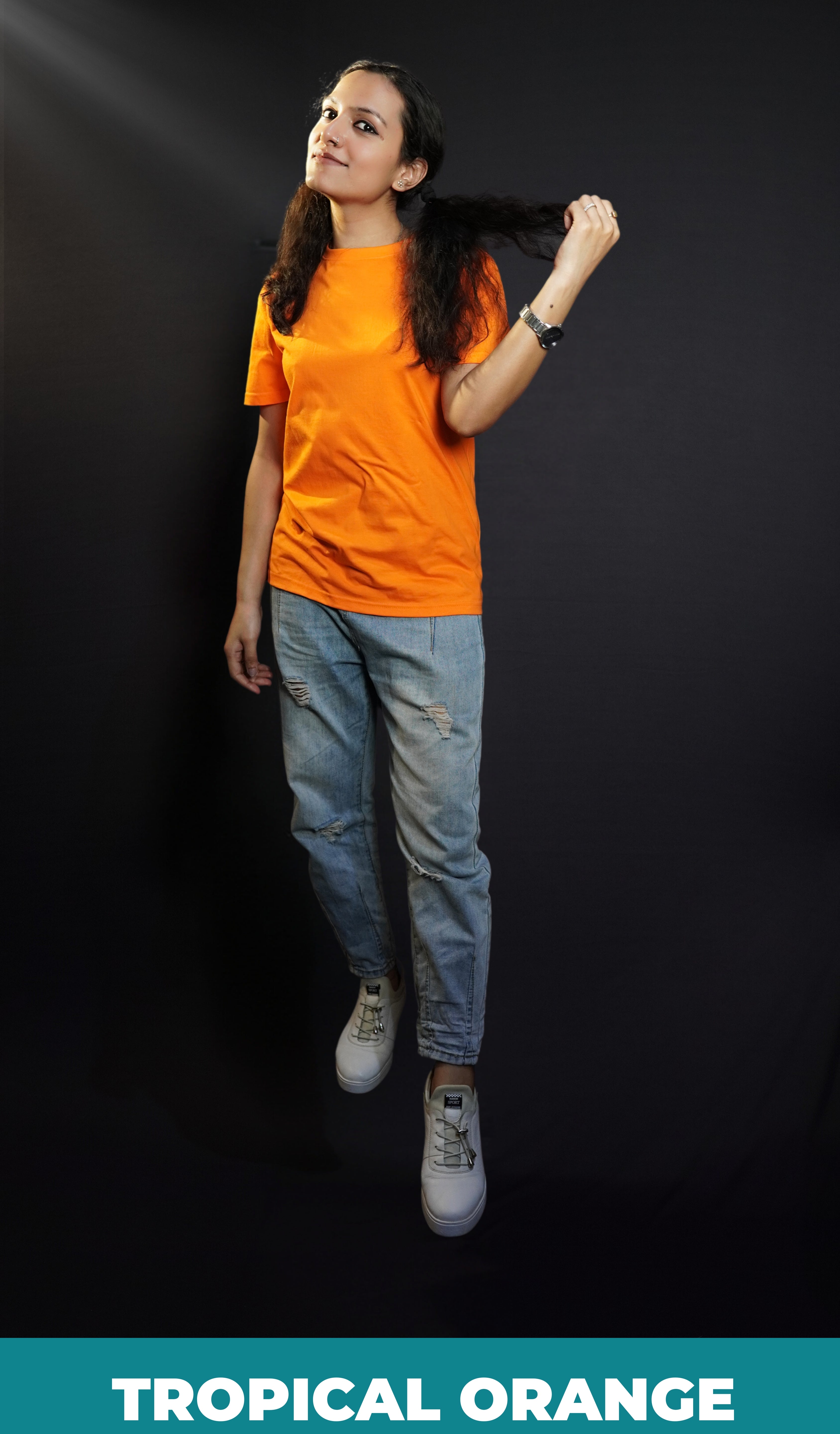 A woman wearing a long length short sleeved round neck plain cotton orange t-shirt, posing with her hand pulling a section of her short hair, showcasing a relaxed cozy fit-Muselot
