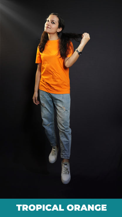 A woman wearing a long length short sleeved round neck plain cotton orange t-shirt, posing with her hand pulling a section of her short hair, showcasing a relaxed cozy fit-Muselot