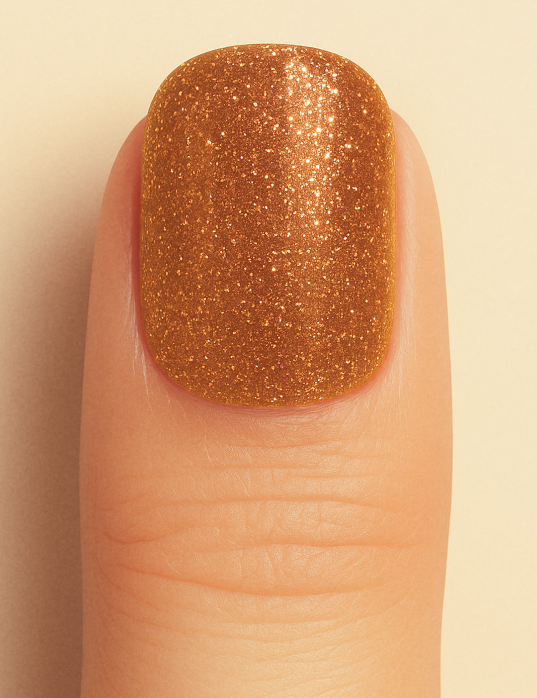 A close-up shot of a model’s finger wearing Warm Gold Glitter nail stickies, showcasing the dazzling golden shade packed with fine glitter particles, highlighting the sparkle and glam of solid glitter nail art with a smooth, glossy finish – Muselot.