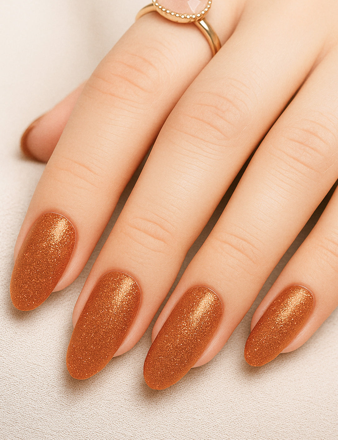 A shot of a model’s hand wearing Warm Gold Glitter nail stickies, showcasing the shimmering golden shade with a full glitter finish, highlighting the sparkle and festive charm of bold nail art in a smooth, salon-style look – Muselot.