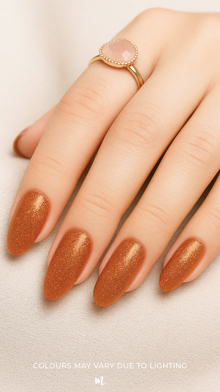 A shot of a model’s hand wearing Warm Gold Glitter nail stickies, showcasing the shimmering golden shade with a full glitter finish, highlighting the sparkle and festive charm of bold nail art in a smooth, salon-style look – Muselot.